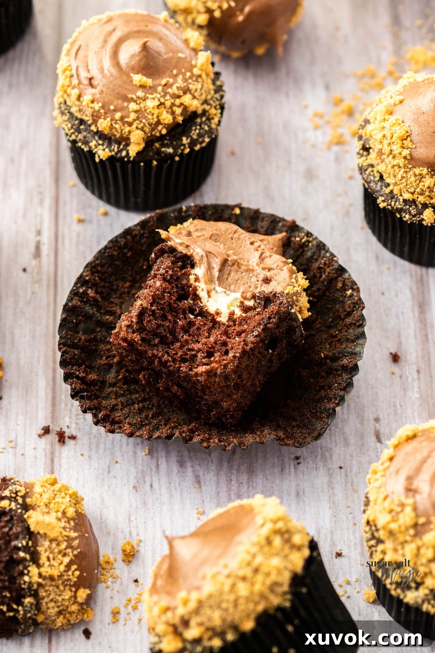 A perfectly baked chocolate cheesecake cupcake, gently broken open to reveal its creamy, luscious cheesecake filling nestled within the moist chocolate cake.