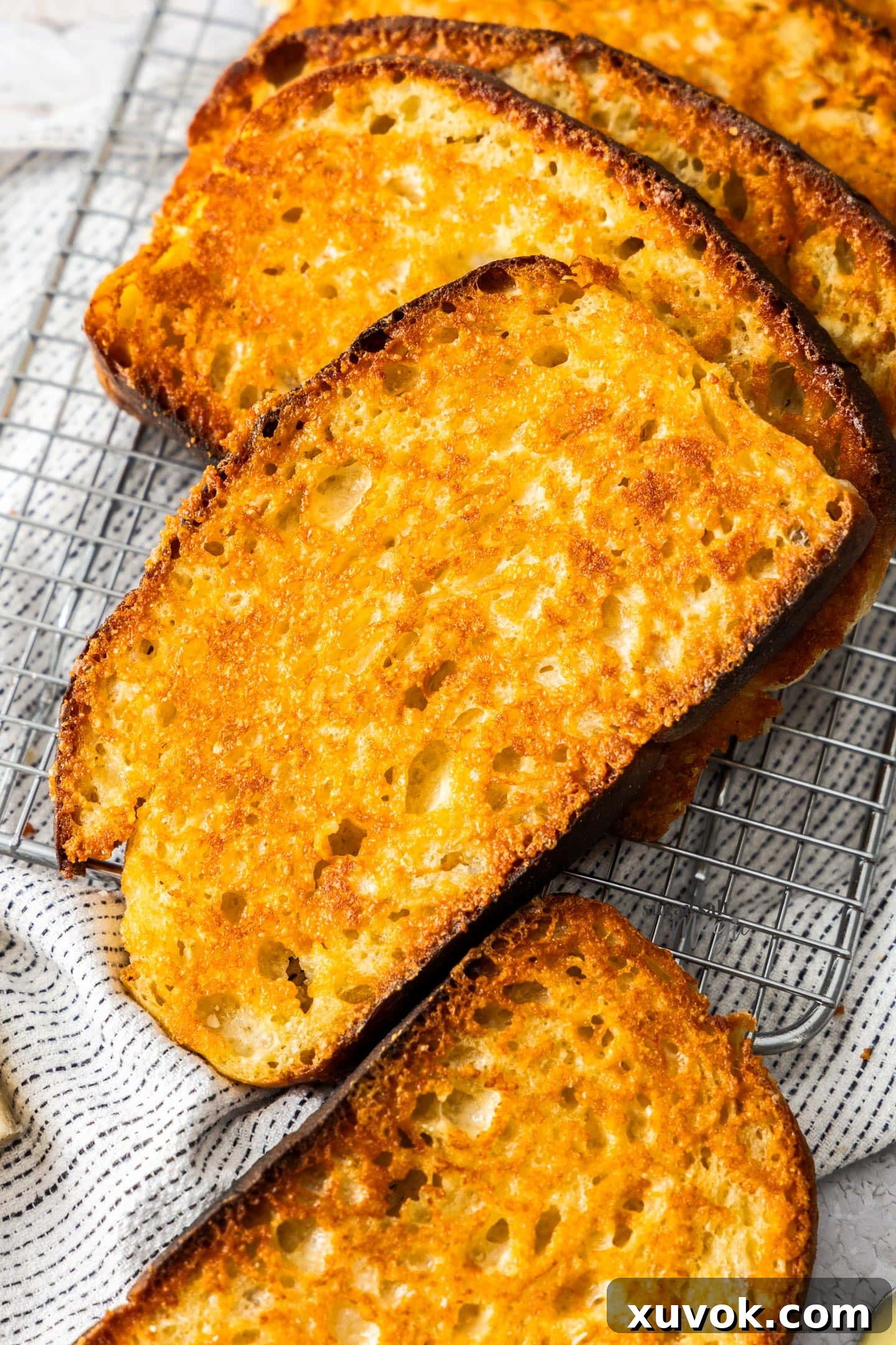 Extreme closeup of a slice of sizzler cheese toast, showing its golden-brown, crispy edges and melted cheese.