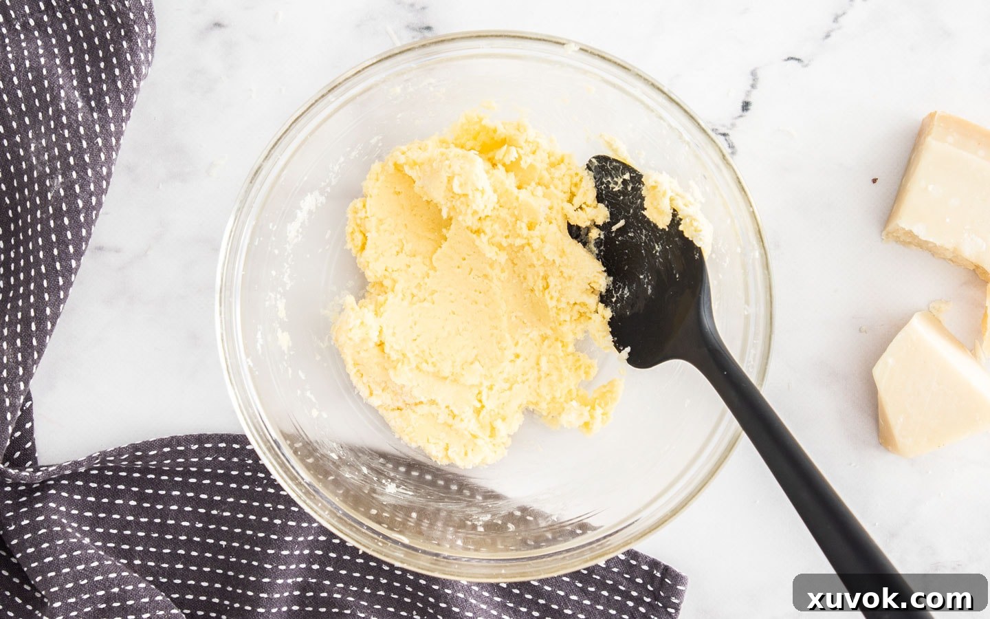 Softened butter and finely grated parmesan cheese mixed together in a bowl, forming a smooth paste.