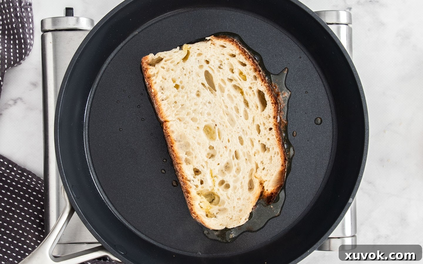 A slice of Sizzler cheese toast cooking butter-side down in a hot skillet, becoming golden brown.