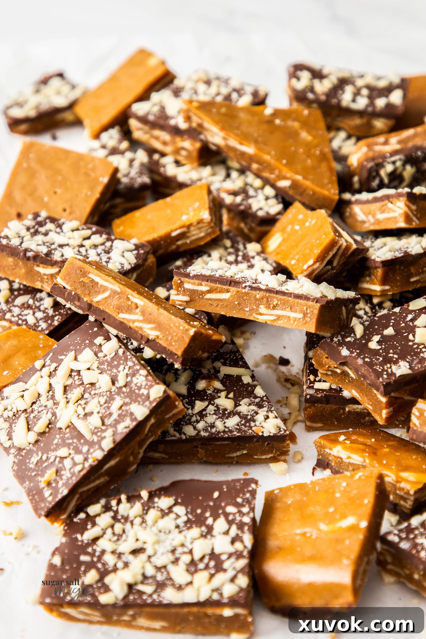 A glorious pile of golden, chocolate-covered almond buttercrunch toffee pieces, glistening and ready to be enjoyed.