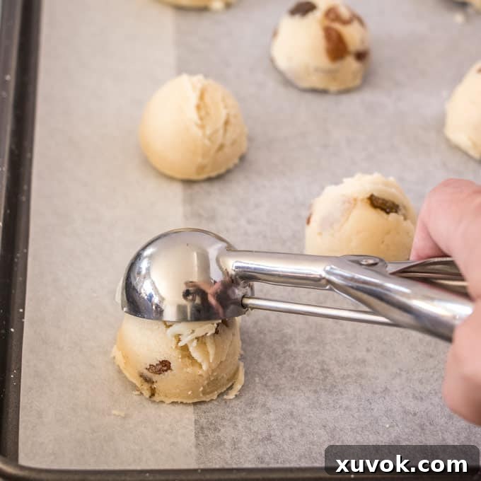 Scooping the dough for Buttery Sultana Cookies onto a baking sheet.