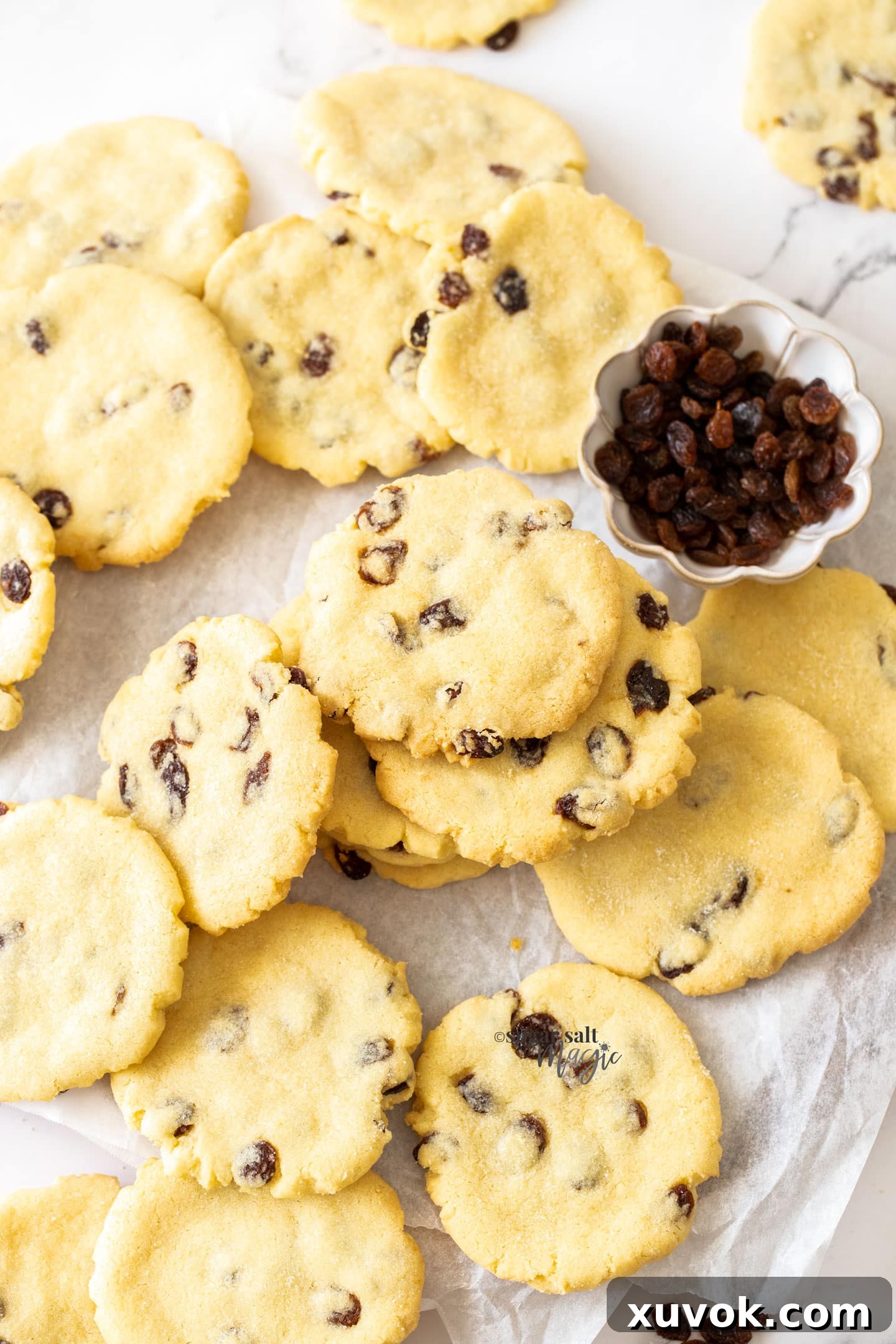 A pile of sultana filled cookies with a small bowl of sultanas, perfect for snacking or gifting.