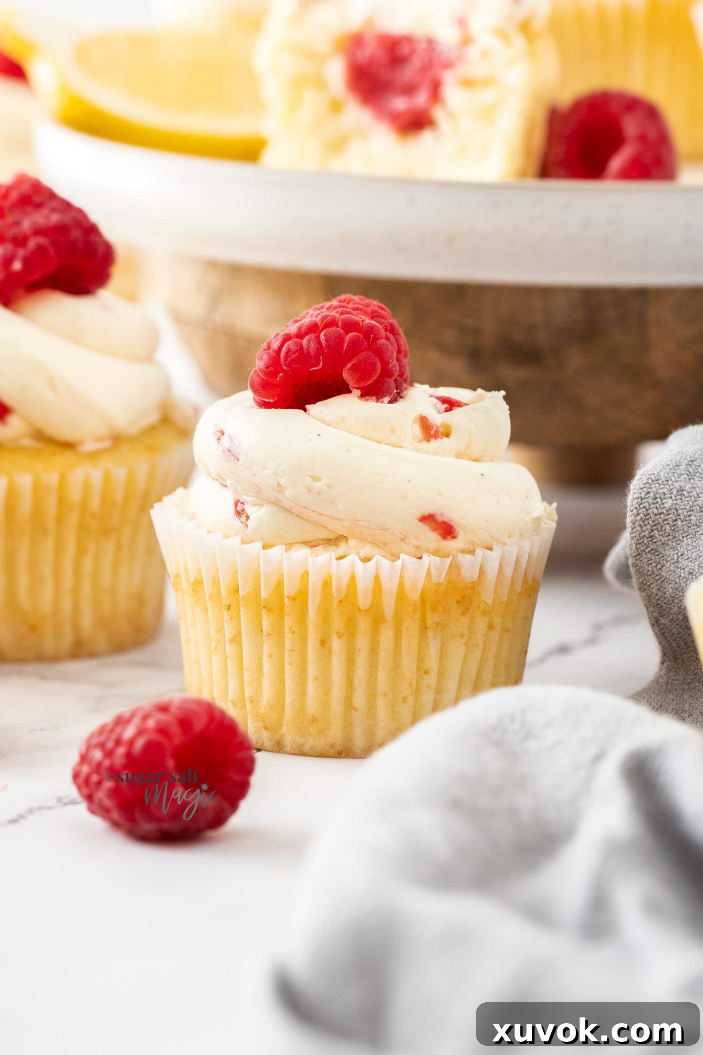 Closeup of a cupcake with a raspberry on top.