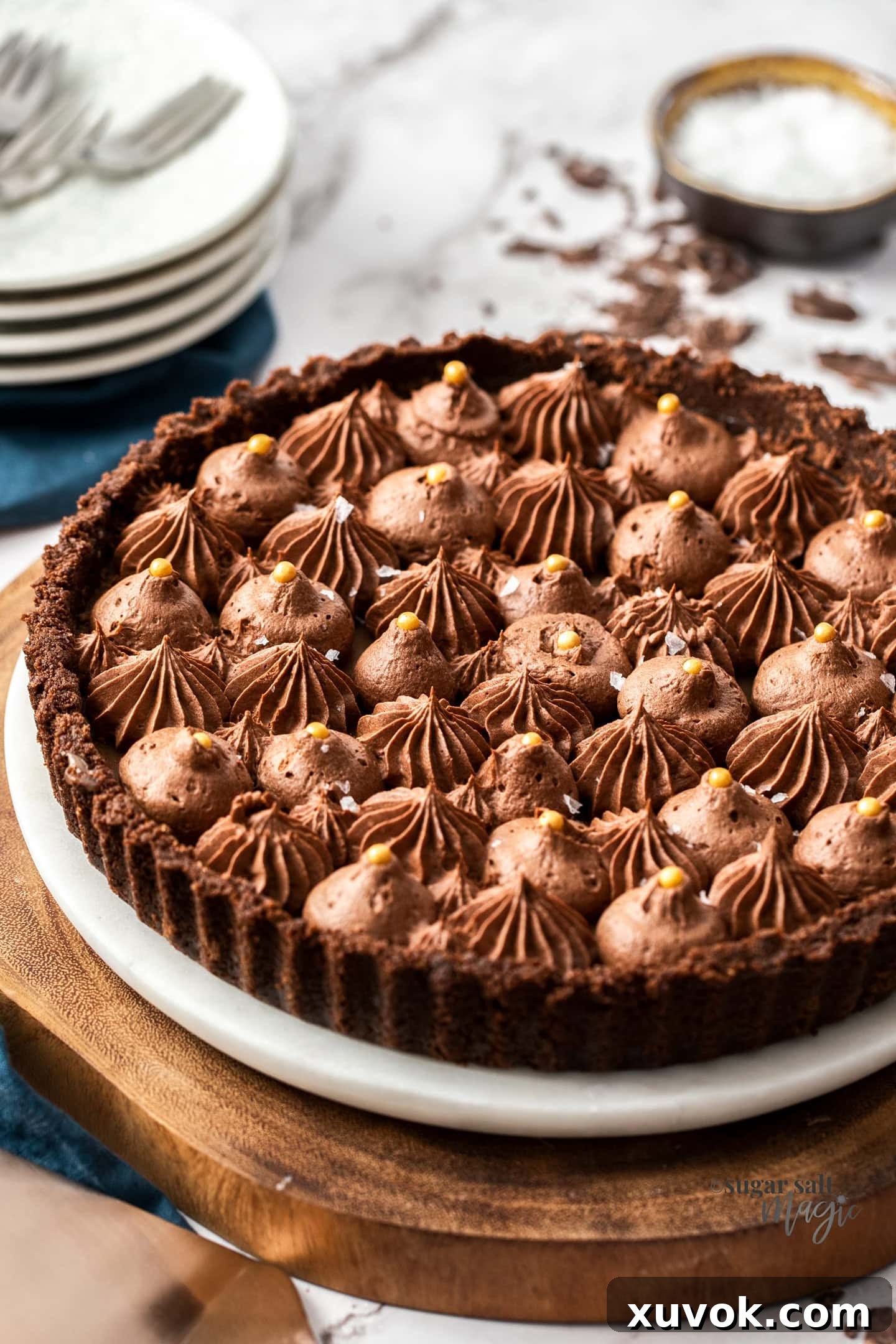 The salted caramel chocolate tart on a platter, ready to slice and serve.