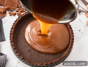 Caramel being poured into a chocolate cookie tart shell.