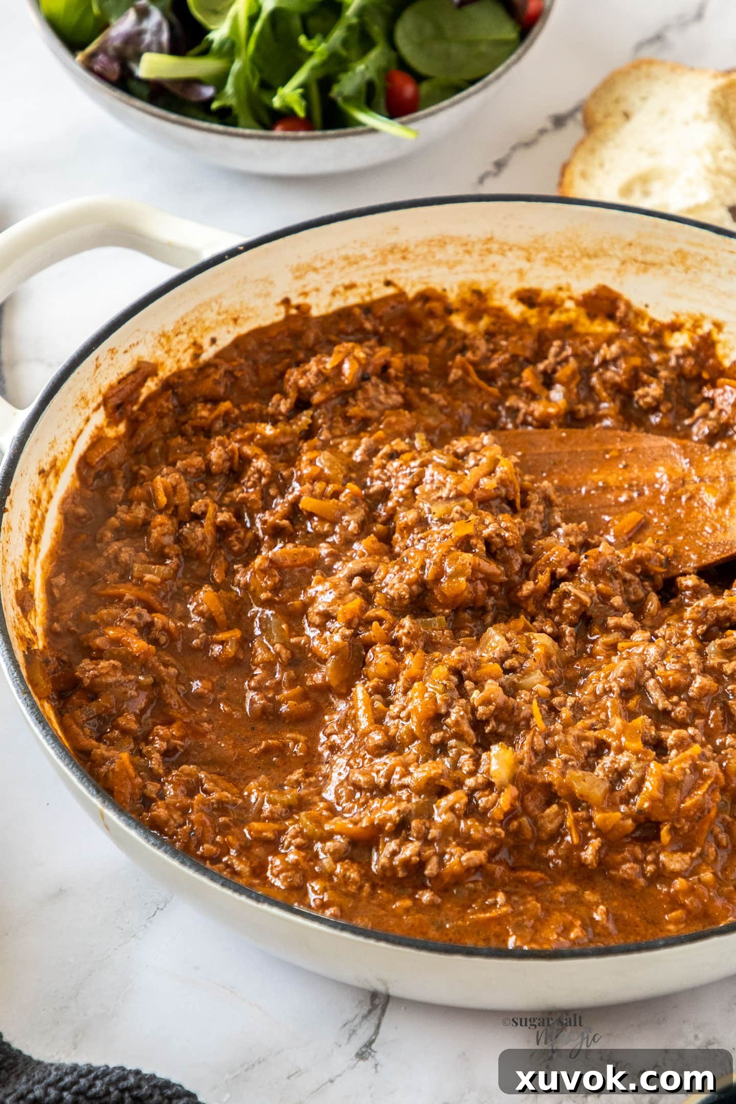 A white casserole dish filled with bolognese sauce.