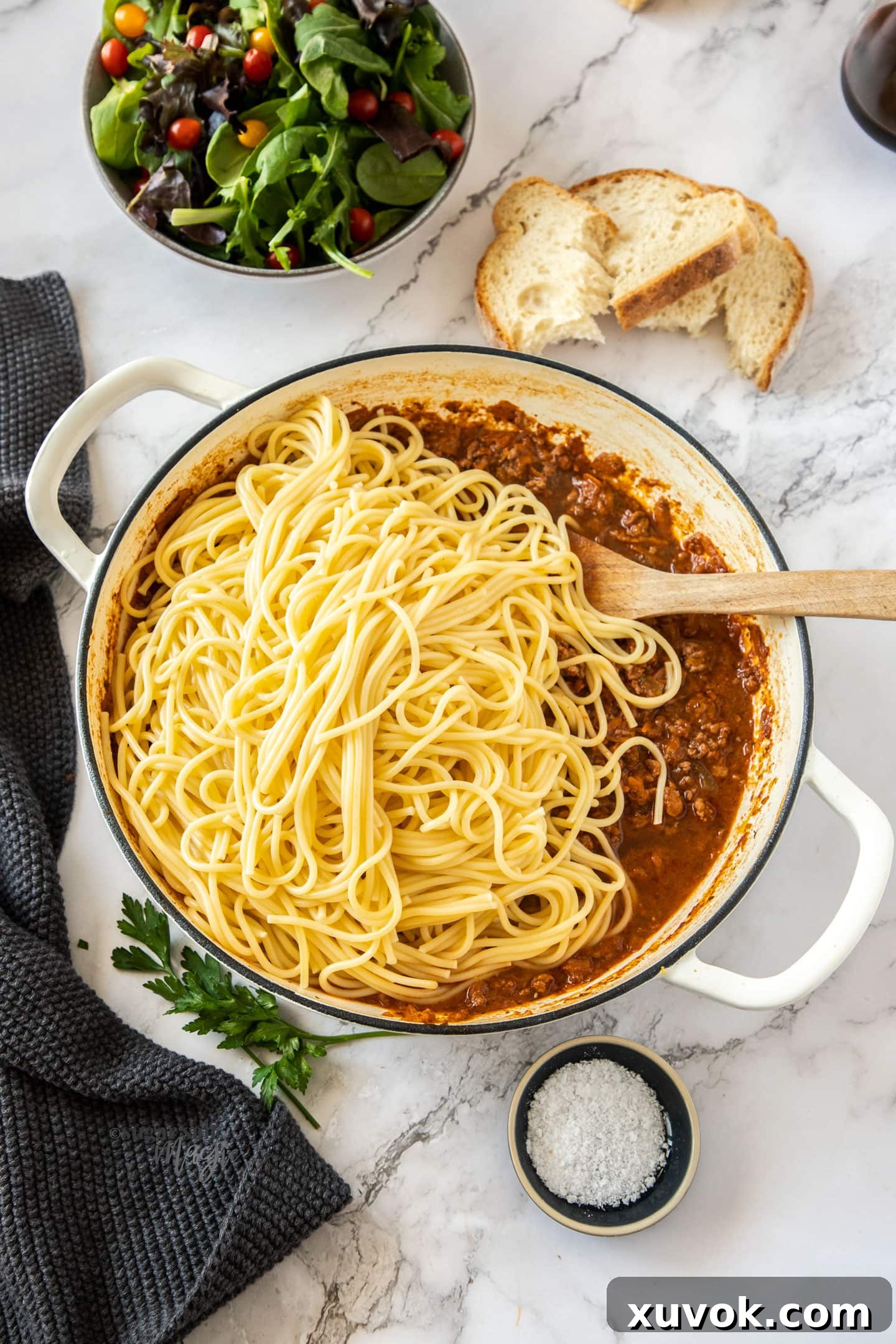 cooked spaghetti on top of meat sauce in a white casserole pan.