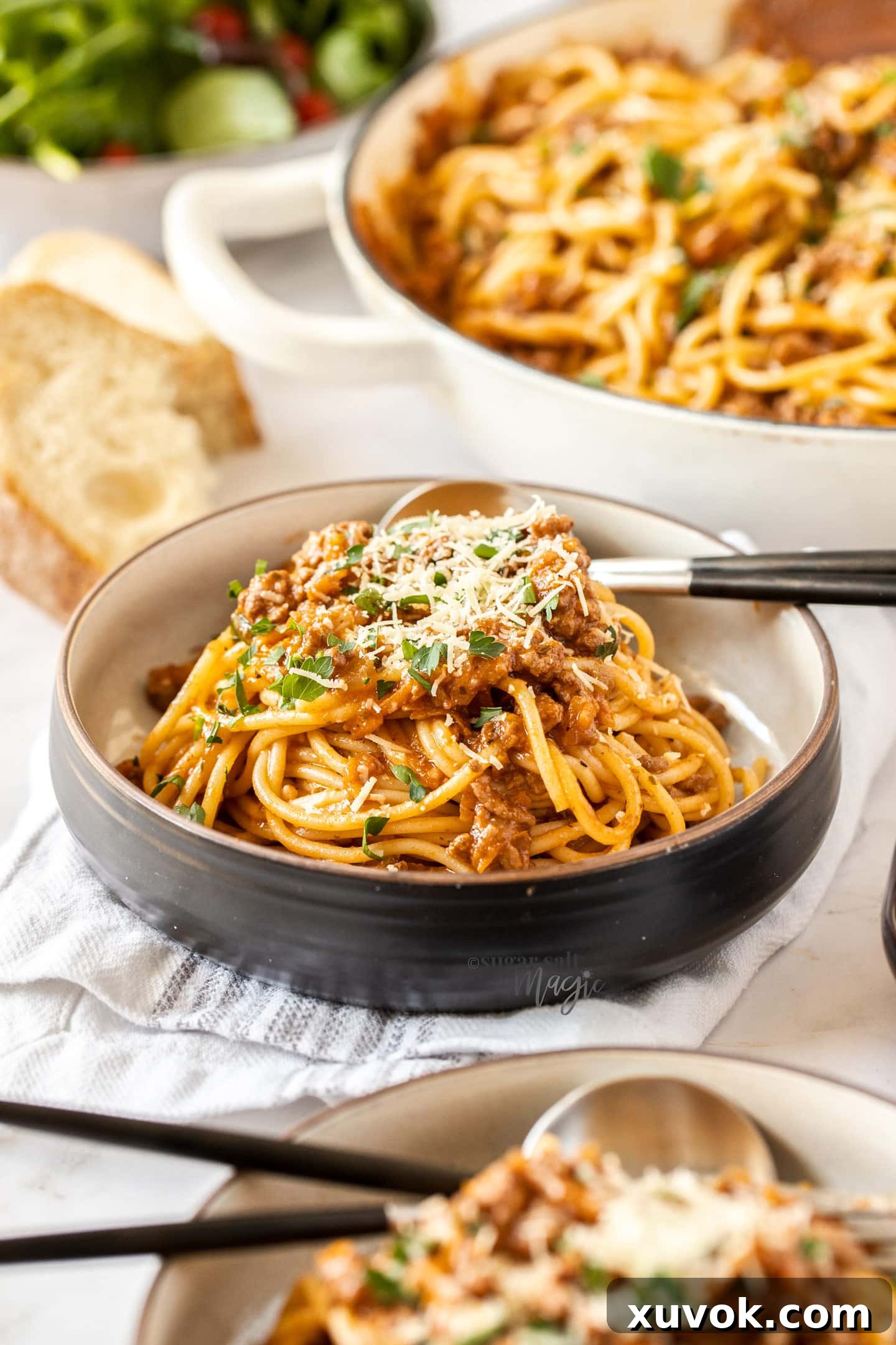 A black bowl filled with spaghetti bolognese.