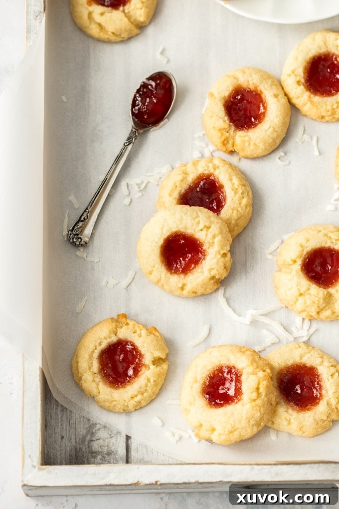 Birdseye view of coconut jam drops on a grey tray, showcasing their golden edges and vibrant jam centers.