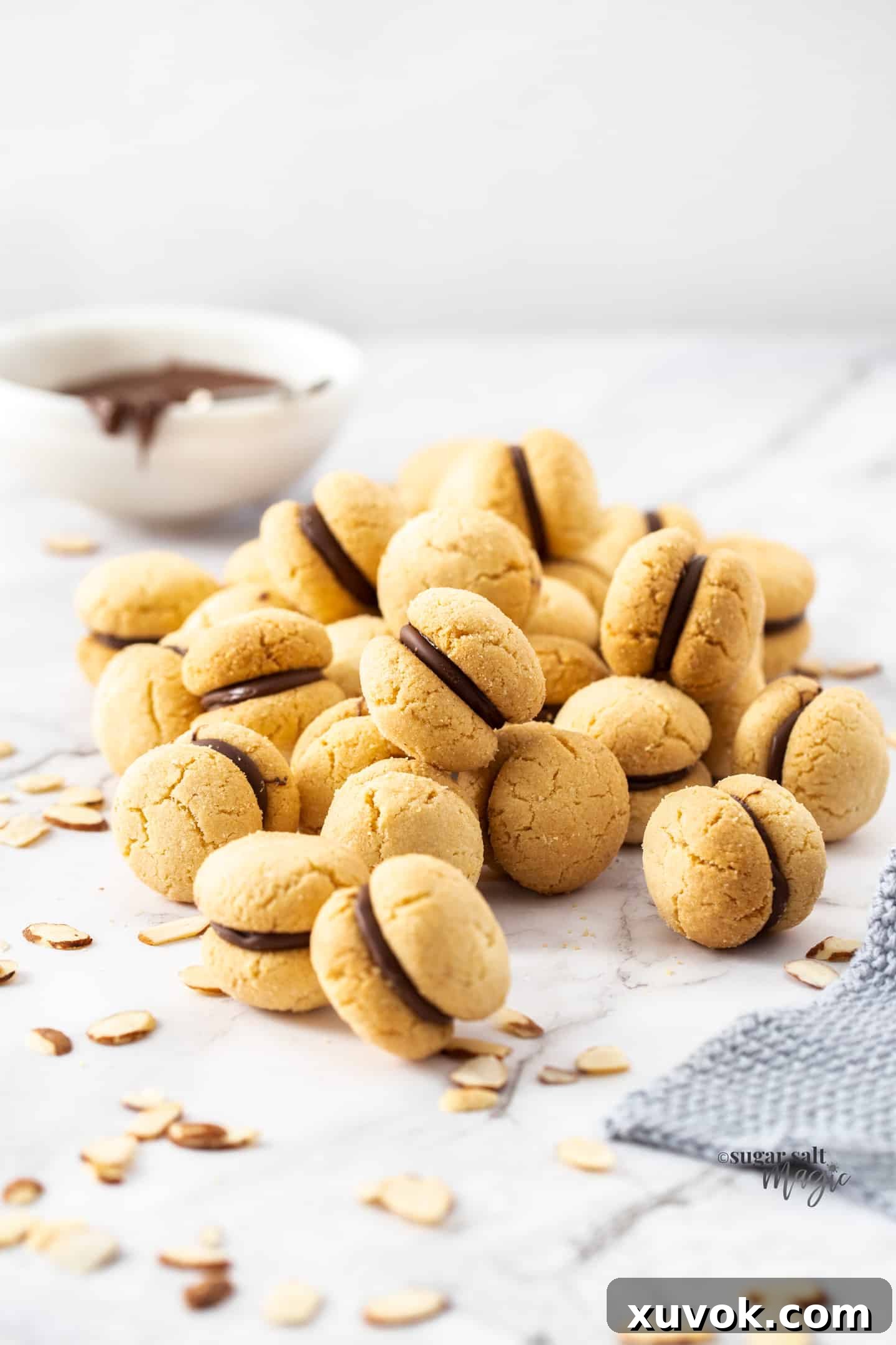 A pile of Baci Di Dama Italian almond shortbread cookies on a marble surface, elegantly arranged and ready to be enjoyed.