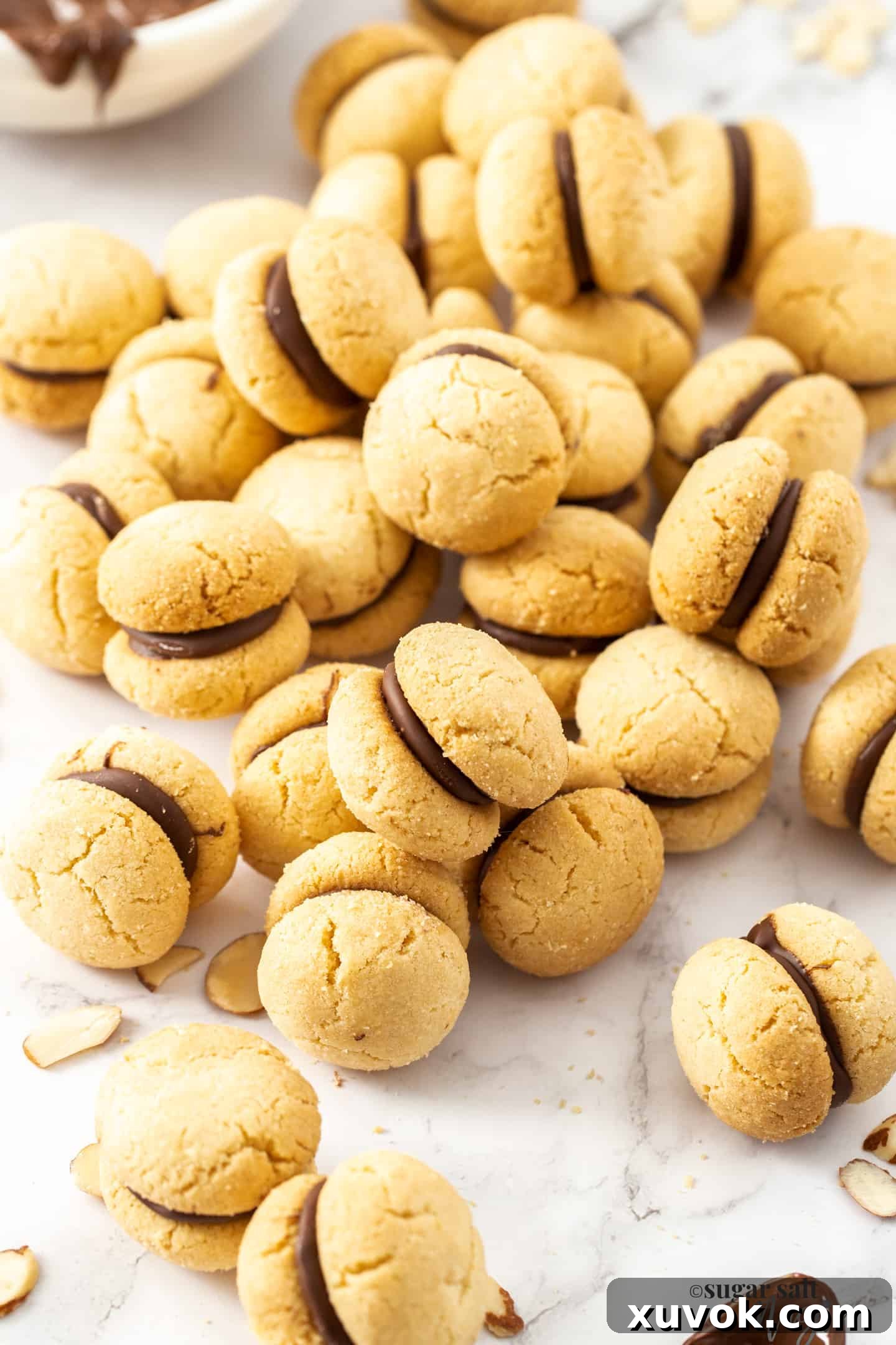 A close-up shot of a lavish pile of Baci Di Dama cookies on a marble surface, emphasizing their delicate texture and inviting appearance.