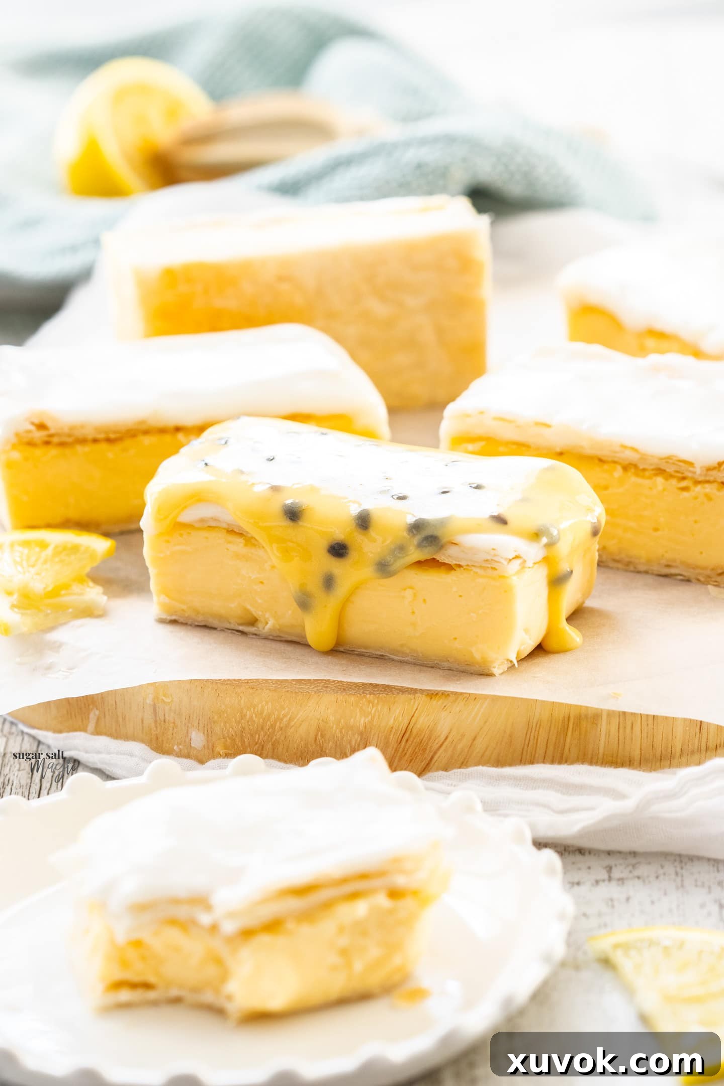 Slices of custard slice on a wooden board, the front one topped with passionfruit icing, highlighting the smooth texture.