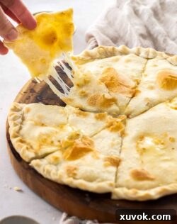 A hand pulling away a piece of focaccia showing the gooey cheese.