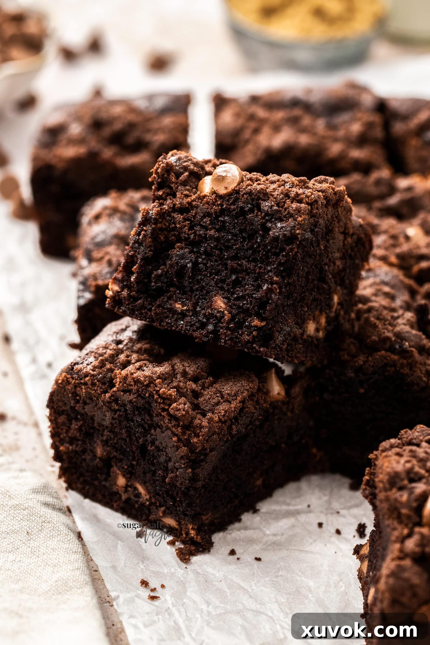 Closeup of two stacked squares of chocolate crumb cake, showcasing its moist interior, melted chocolate chips, and thick, crunchy crumb topping.
