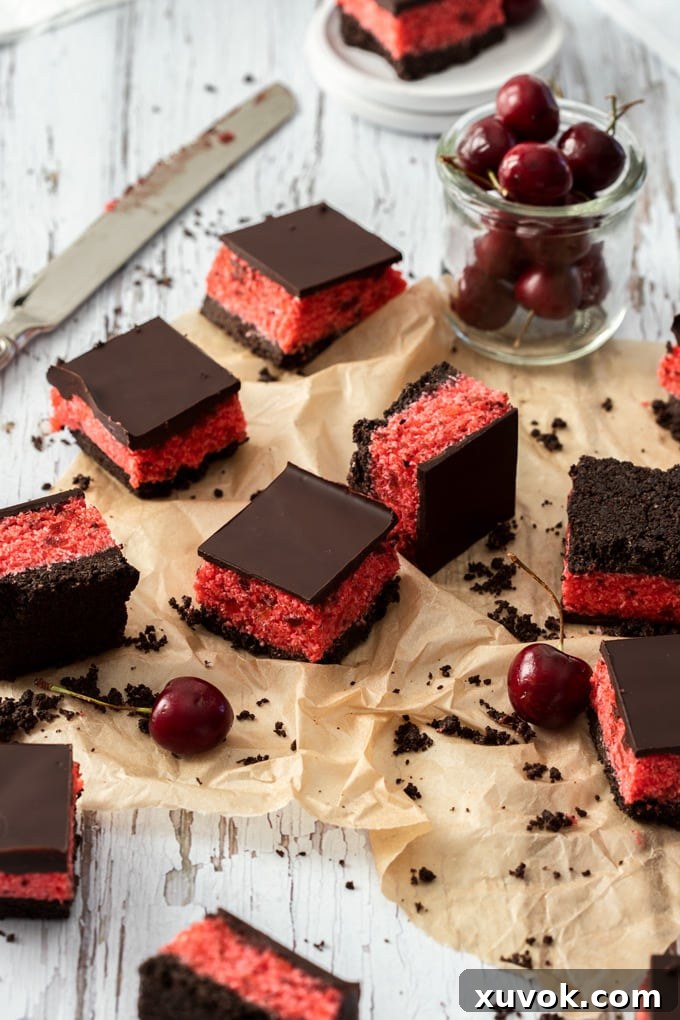 9 randomly placed cherry ripe slices on a piece of brown parchment paper, a glass of cherries at the back.