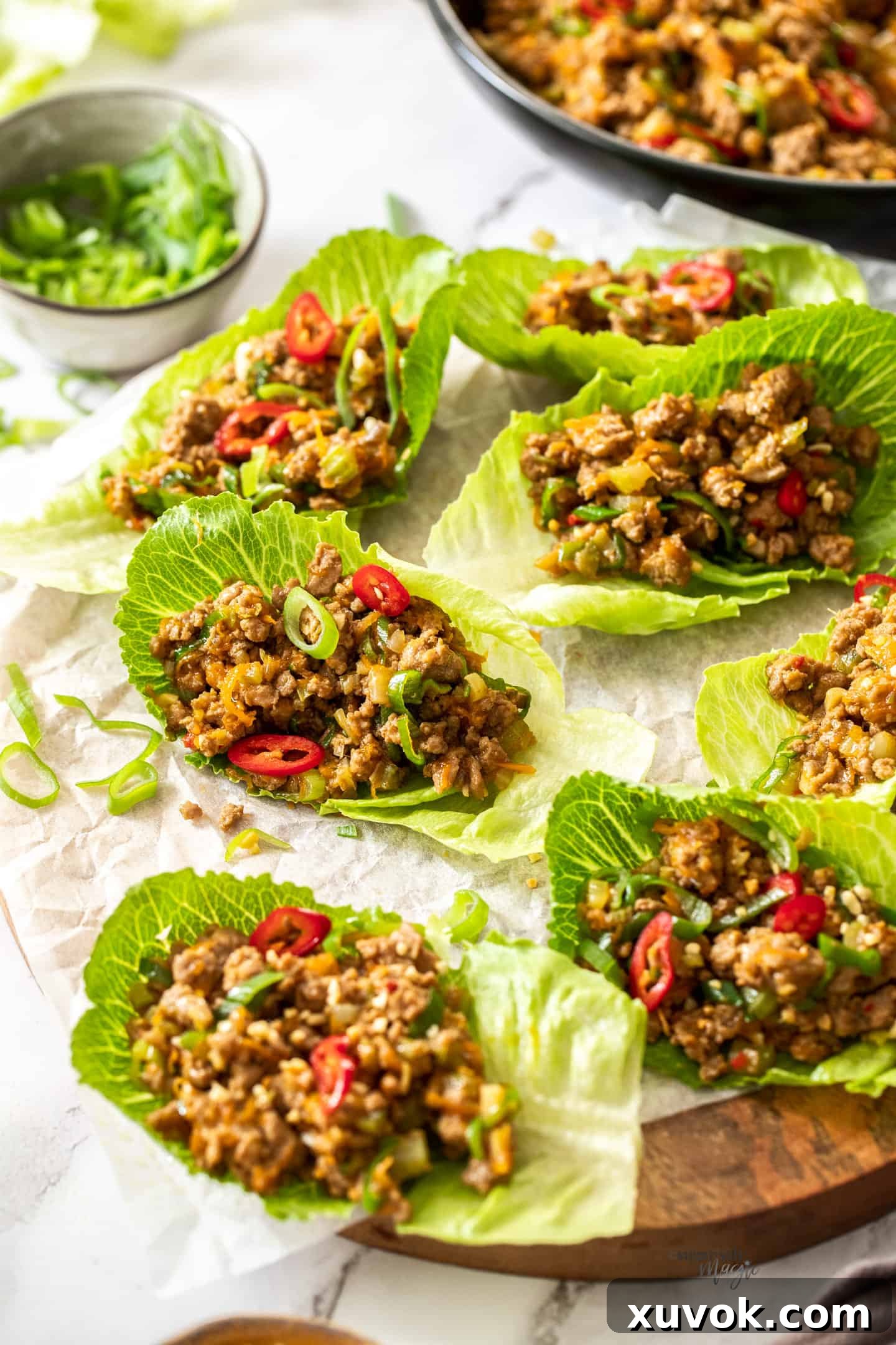 A wooden platter topped with crisp lettuce leaves, generously filled with a vibrant turkey san choy bow mixture, ready to be enjoyed.
