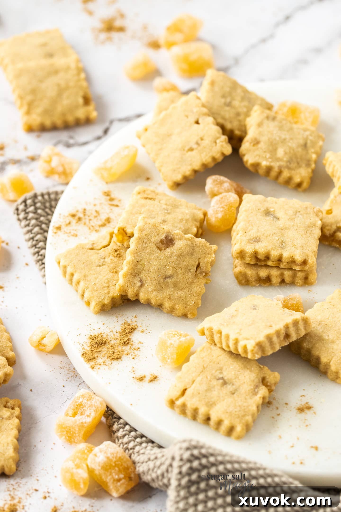 A batch of golden ginger shortbread cookies, perfectly baked and scattered with candied ginger pieces.