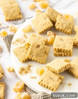 A batch of ginger shortbread cookies surrounded by candied ginger pieces