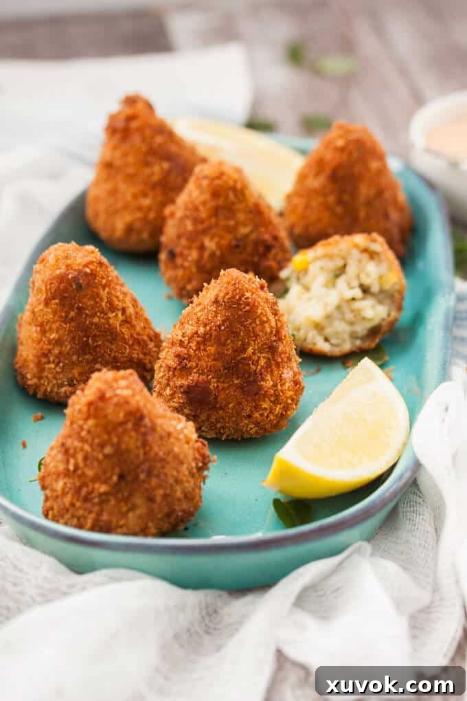 Seven golden sweet corn arancini balls artfully arranged on a rustic turquoise-colored dish, highlighting their crispy texture and inviting presentation.