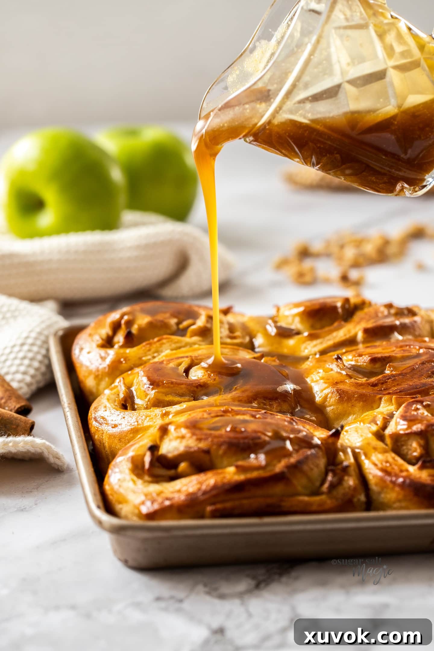 Caramel sauce being poured over cinnamon rolls.