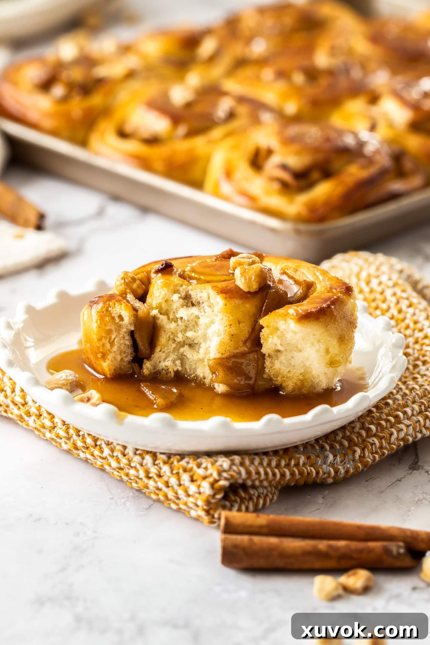 A cinnamon roll covered in caramel sauce sitting on a white plate.