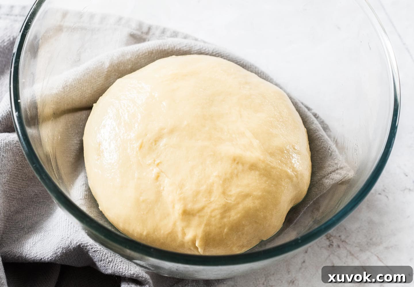 The dough in a glass mixing bowl.