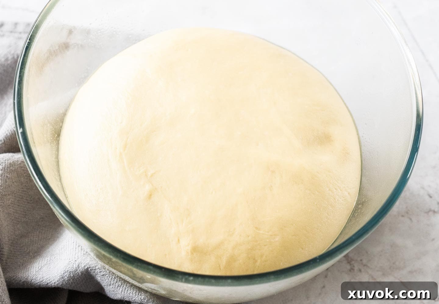 The dough after it has risen in a glass bowl.