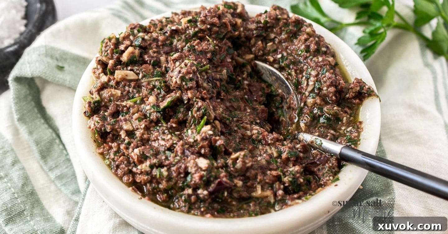 A beautifully presented white bowl filled with creamy Kalamata olive pesto, showcasing its rich texture and inviting color.