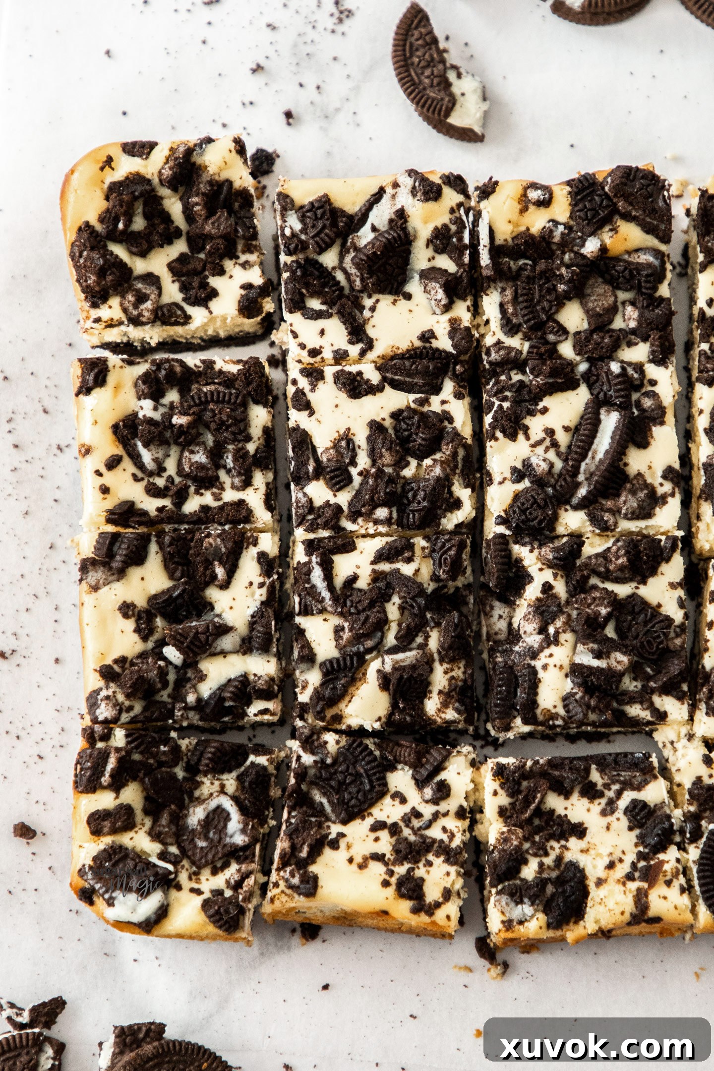 A top-down view of 12 perfectly sliced squares of homemade Oreo cheesecake bars, showcasing the creamy filling and crunchy Oreo layers.