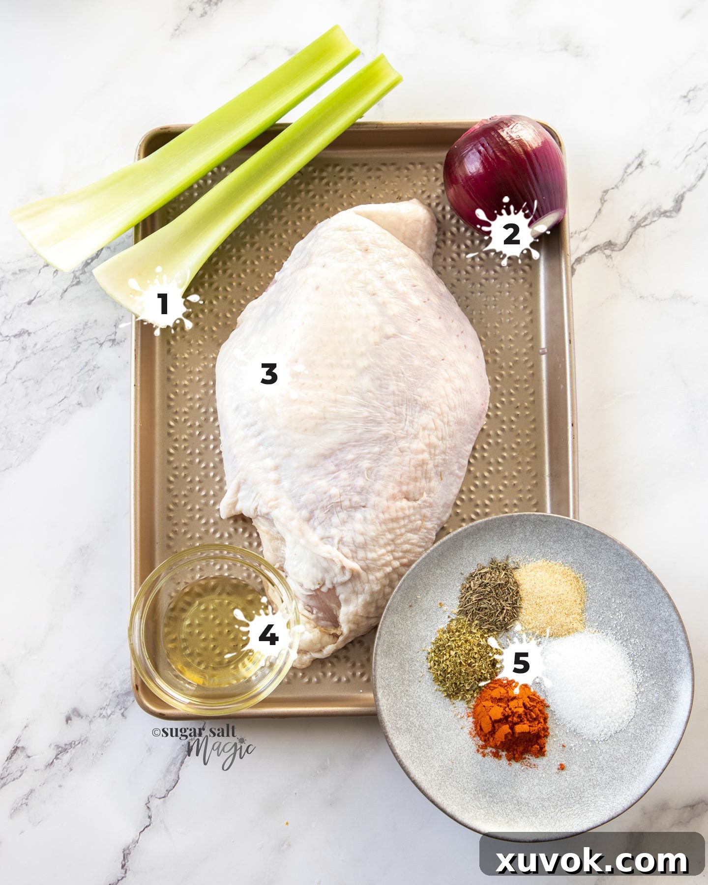 A selection of fresh ingredients for slow cooker turkey breast neatly arranged on a rustic gold baking tray, including a raw turkey breast, chopped celery and onion, and various spice jars.