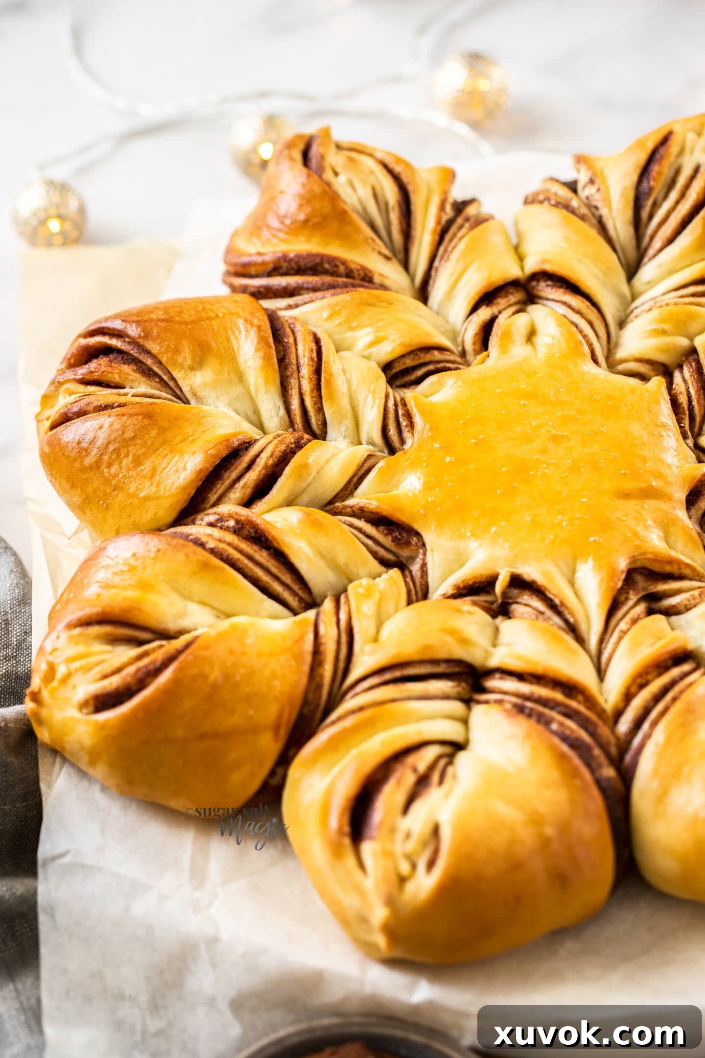 A star shaped bread on a sheet of baking paper, dusted with icing sugar