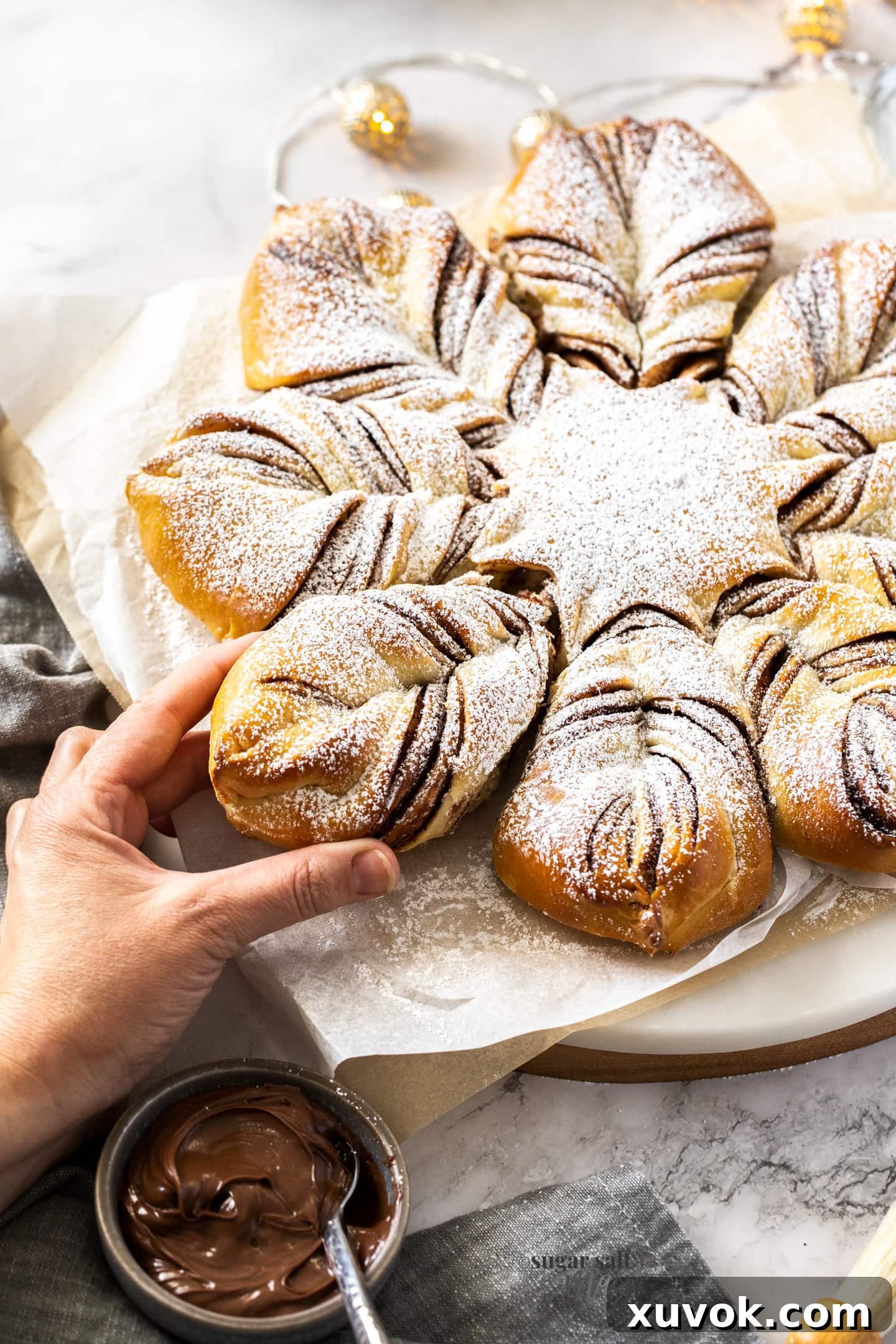 A hand reaching in to pull out a piece of star bread from the center of the tray