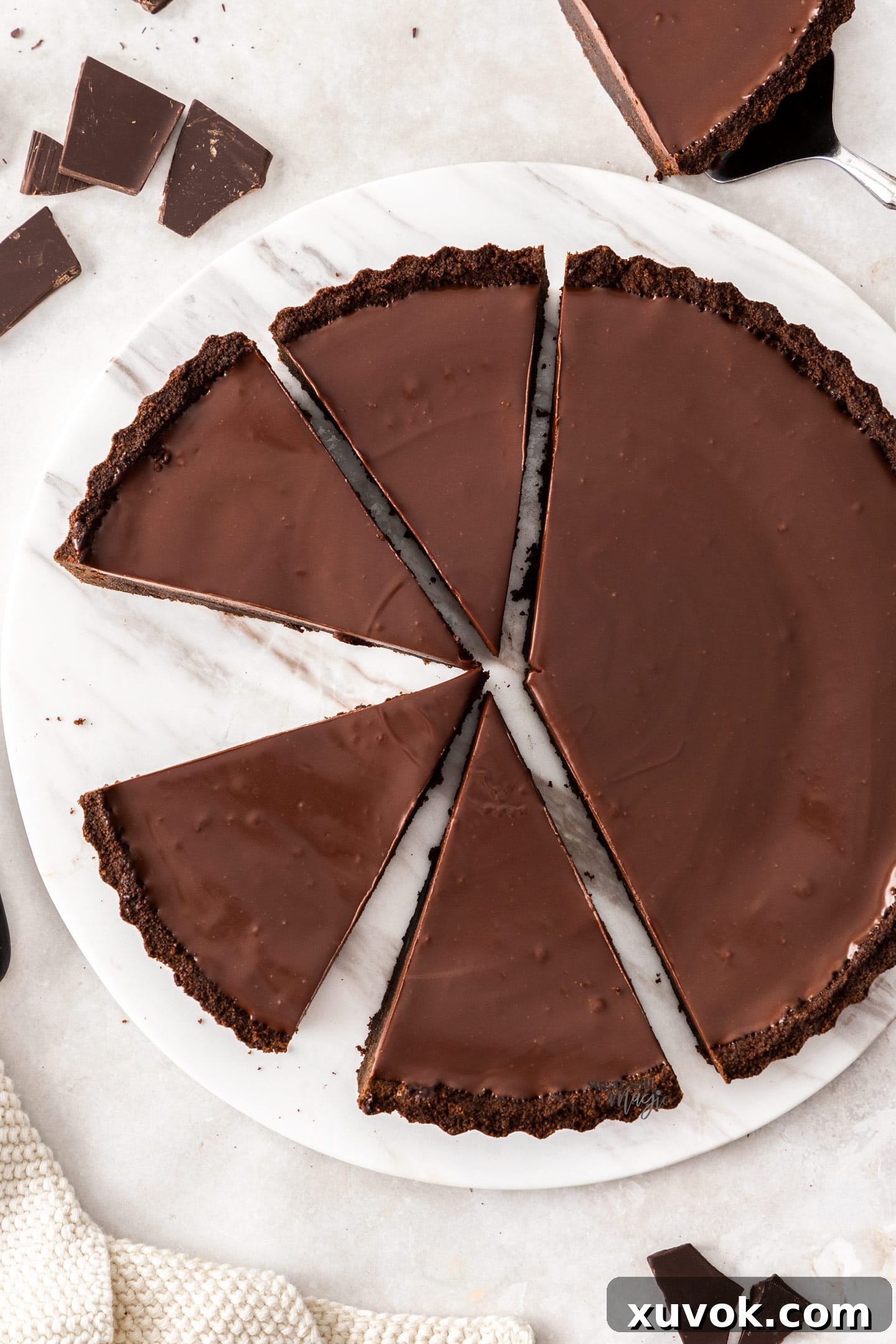 Top down view of a brownie tart cut into slices, highlighting its fudgy texture and ganache topping.