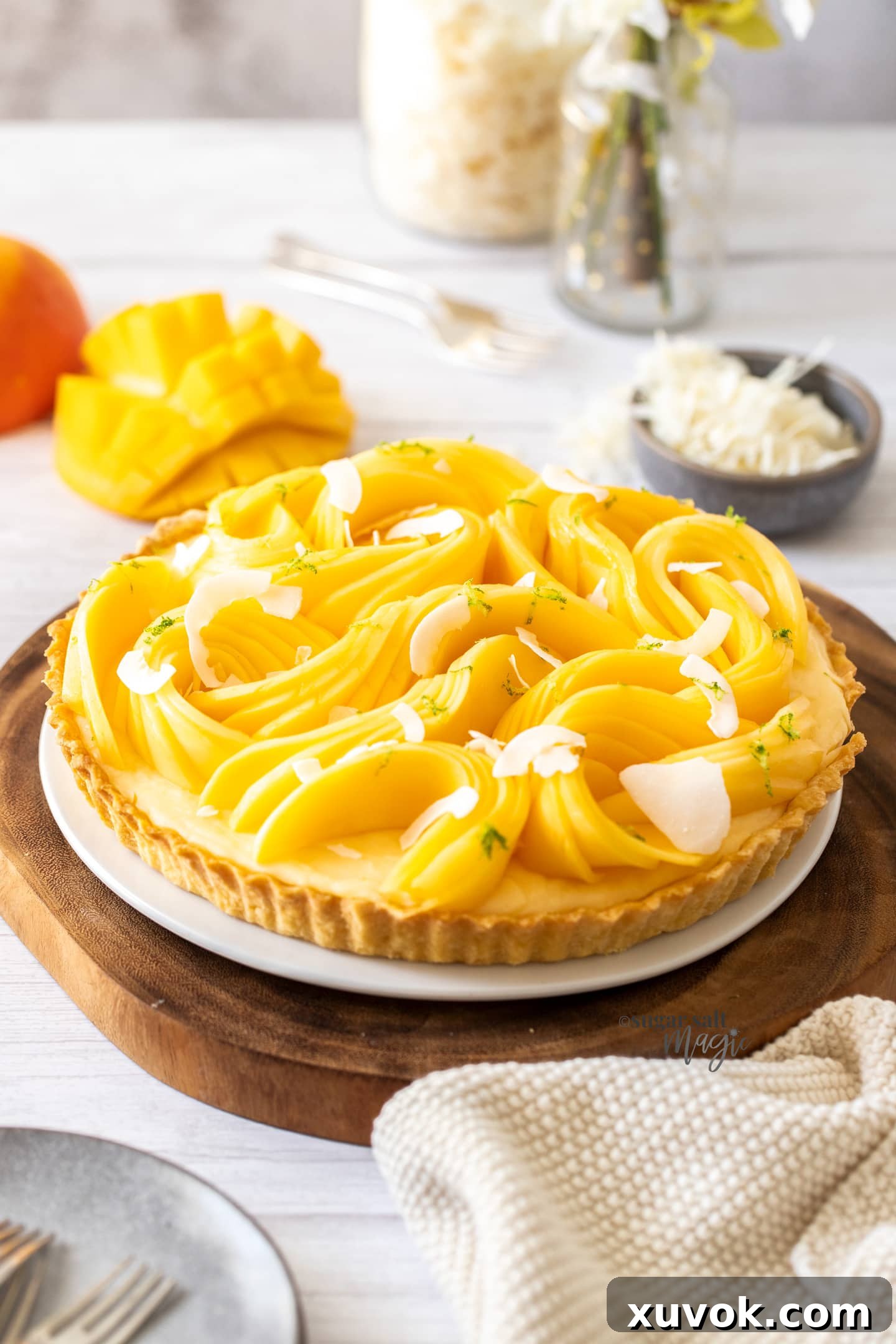 A tart topped with slices of mango on a wooden board.
