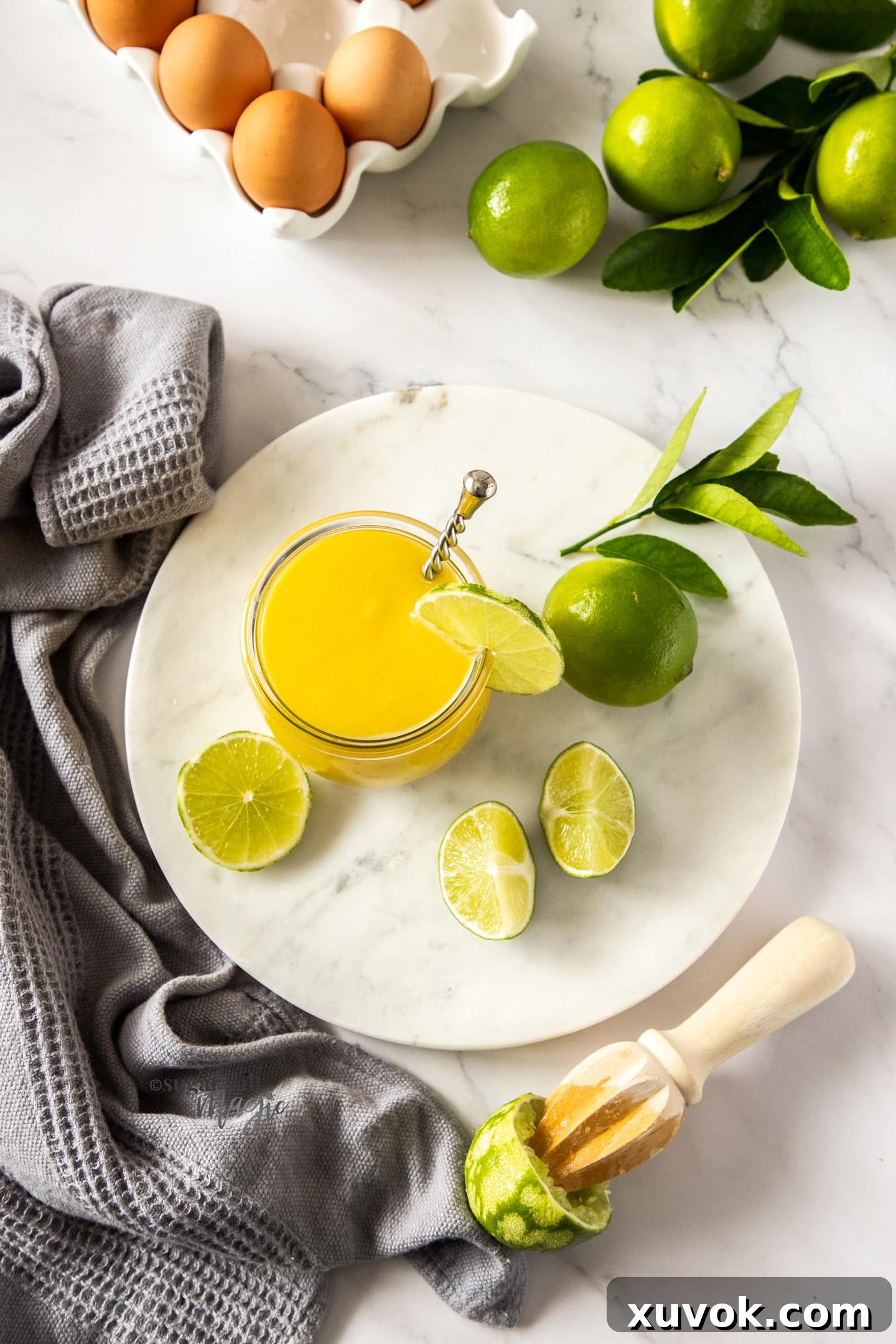 A glass jar filled with luscious lime curd, surrounded by fresh limes and eggs, embodying the freshness and quality of homemade.