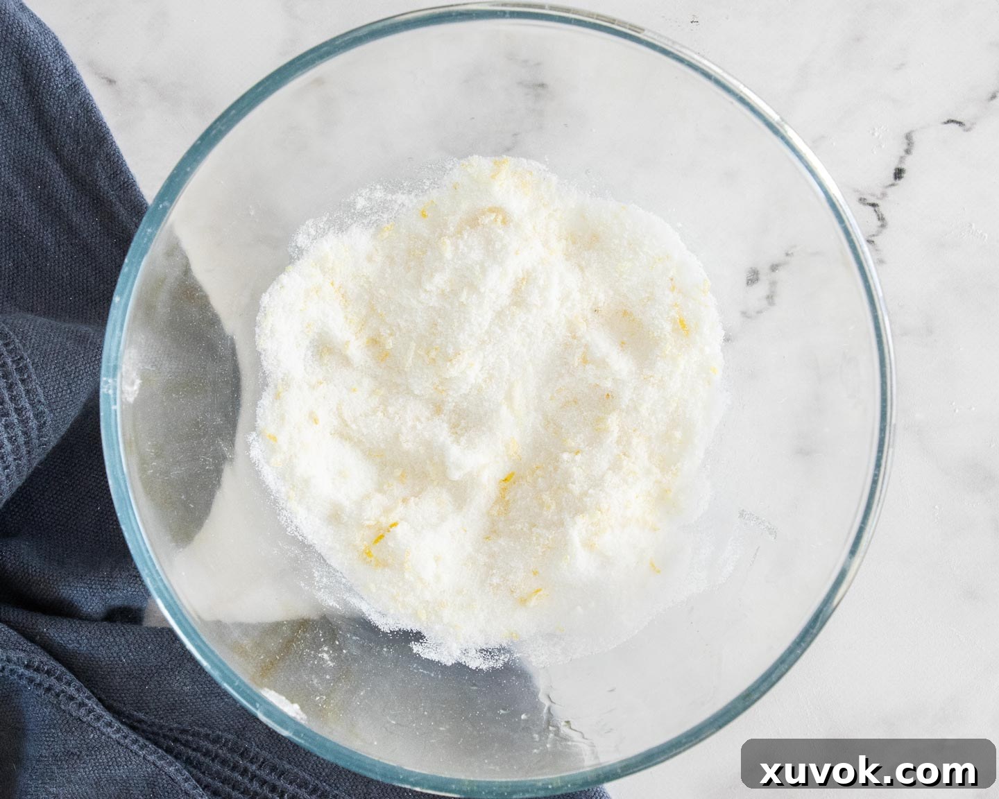 Close-up of lemon zest and sugar blended together in a mixing bowl.