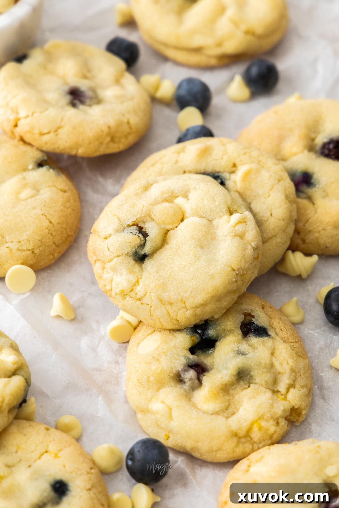 Closeup view of a batch of freshly baked blueberry white chocolate cookies, showing the glistening chocolate and blueberries.