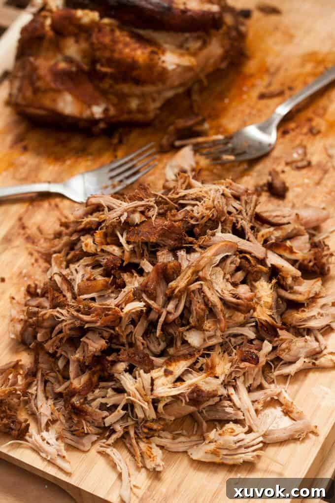A close-up of tender, slow-cooked pulled pork resting on a wooden chopping board, ready to be incorporated into delicious recipes.