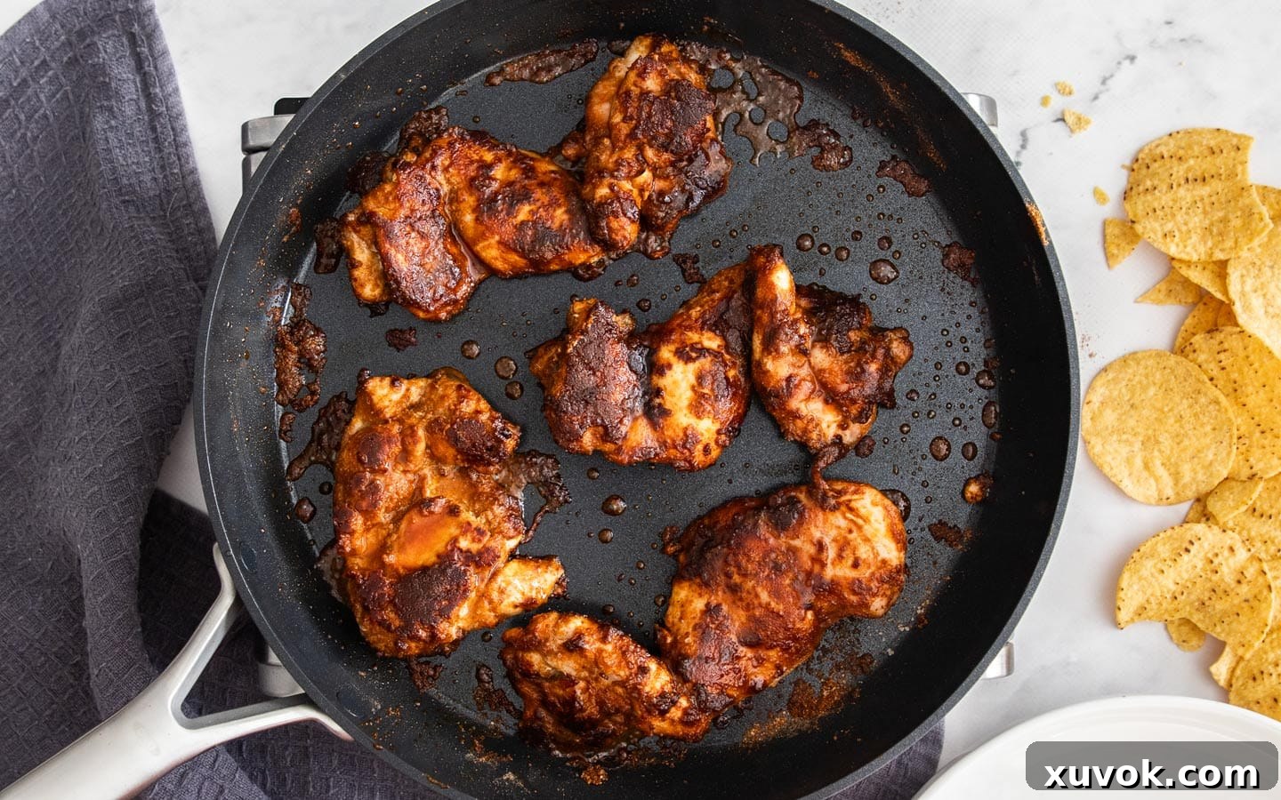 The cooked seasoned chicken thighs resting in a pan, ready to be chopped.