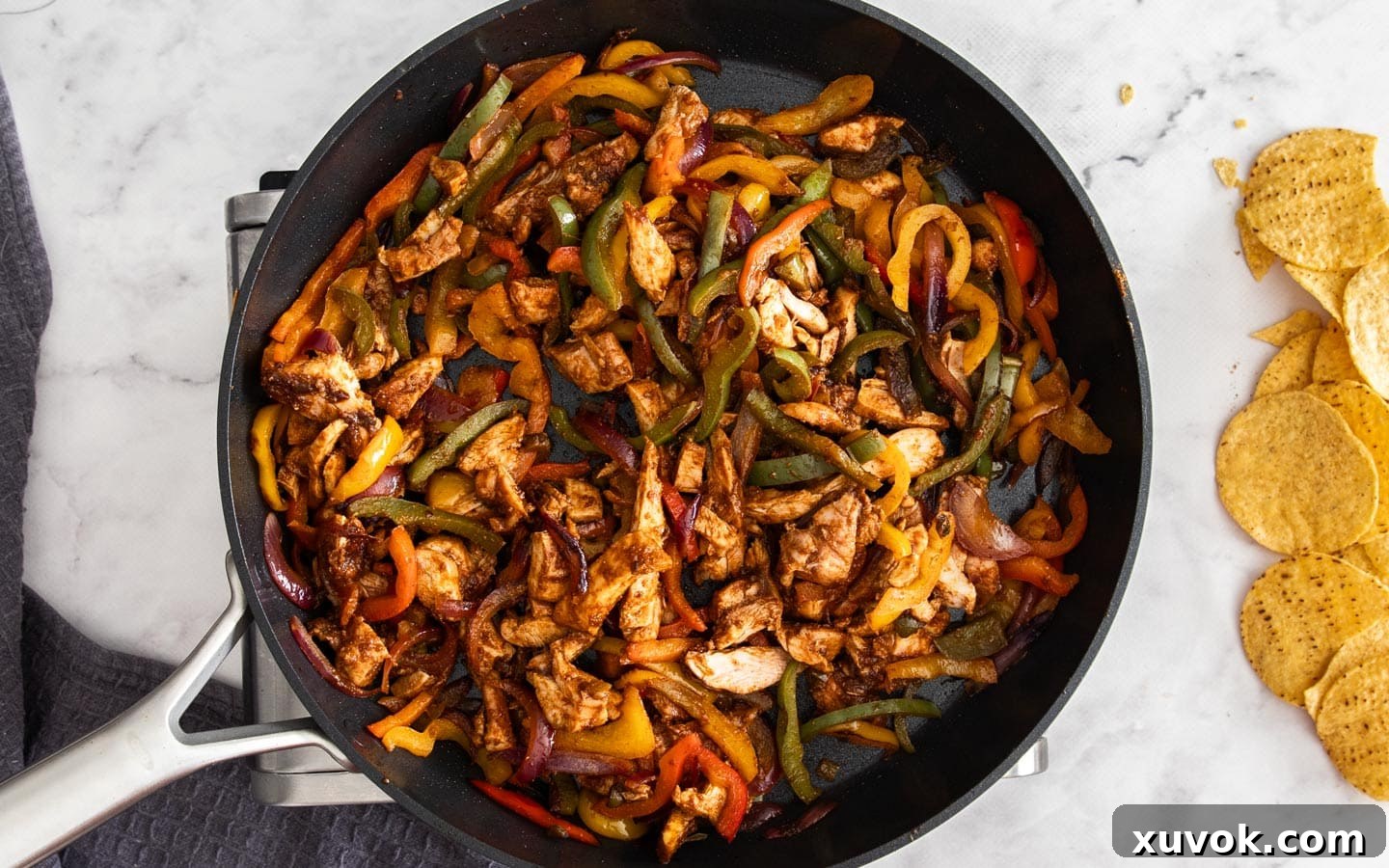 The cooked vegetables and chopped chicken combined in a pan, forming the fajita filling.