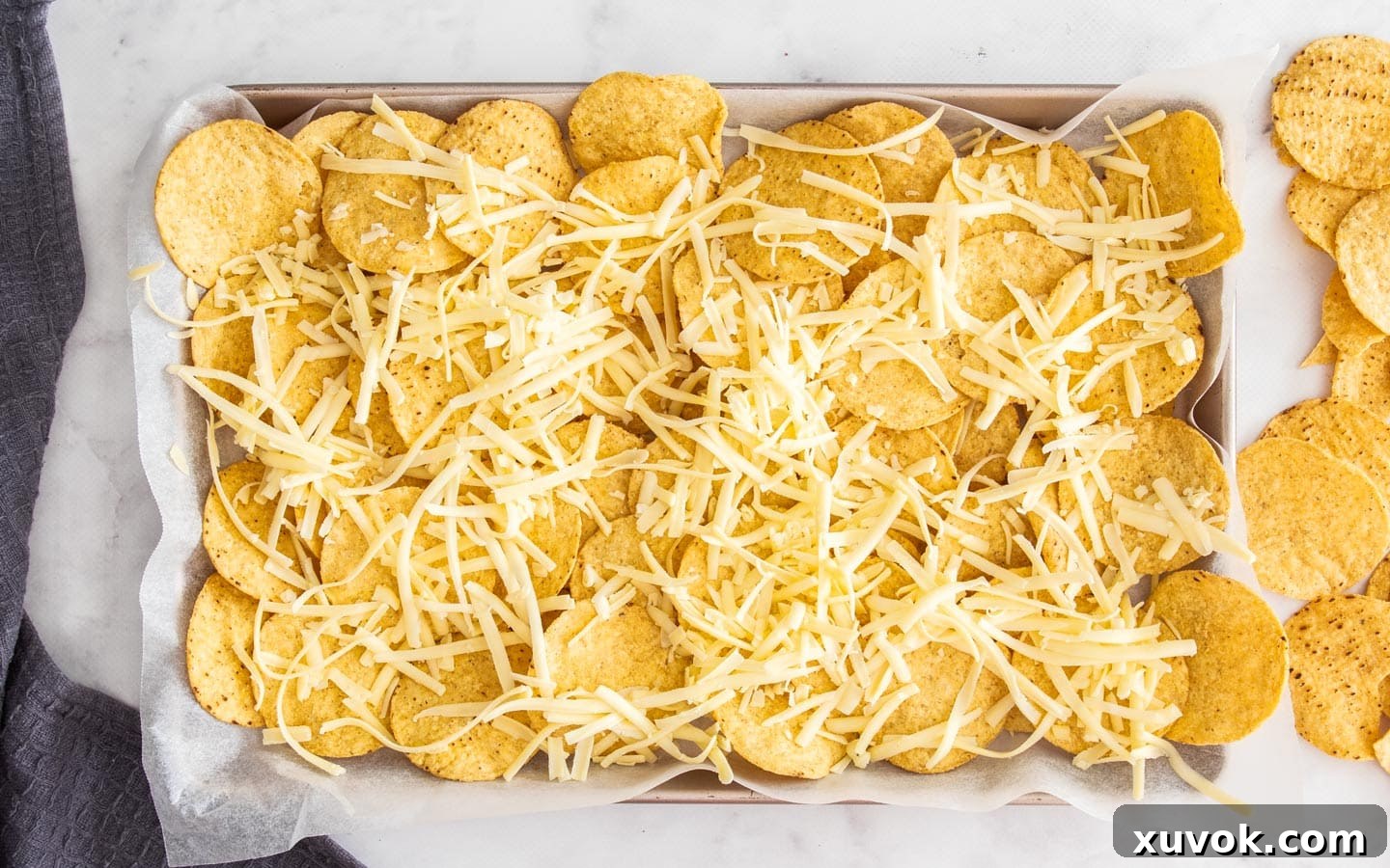 Corn chips topped with a layer of cheese on a baking sheet, ready for the fajita mixture.