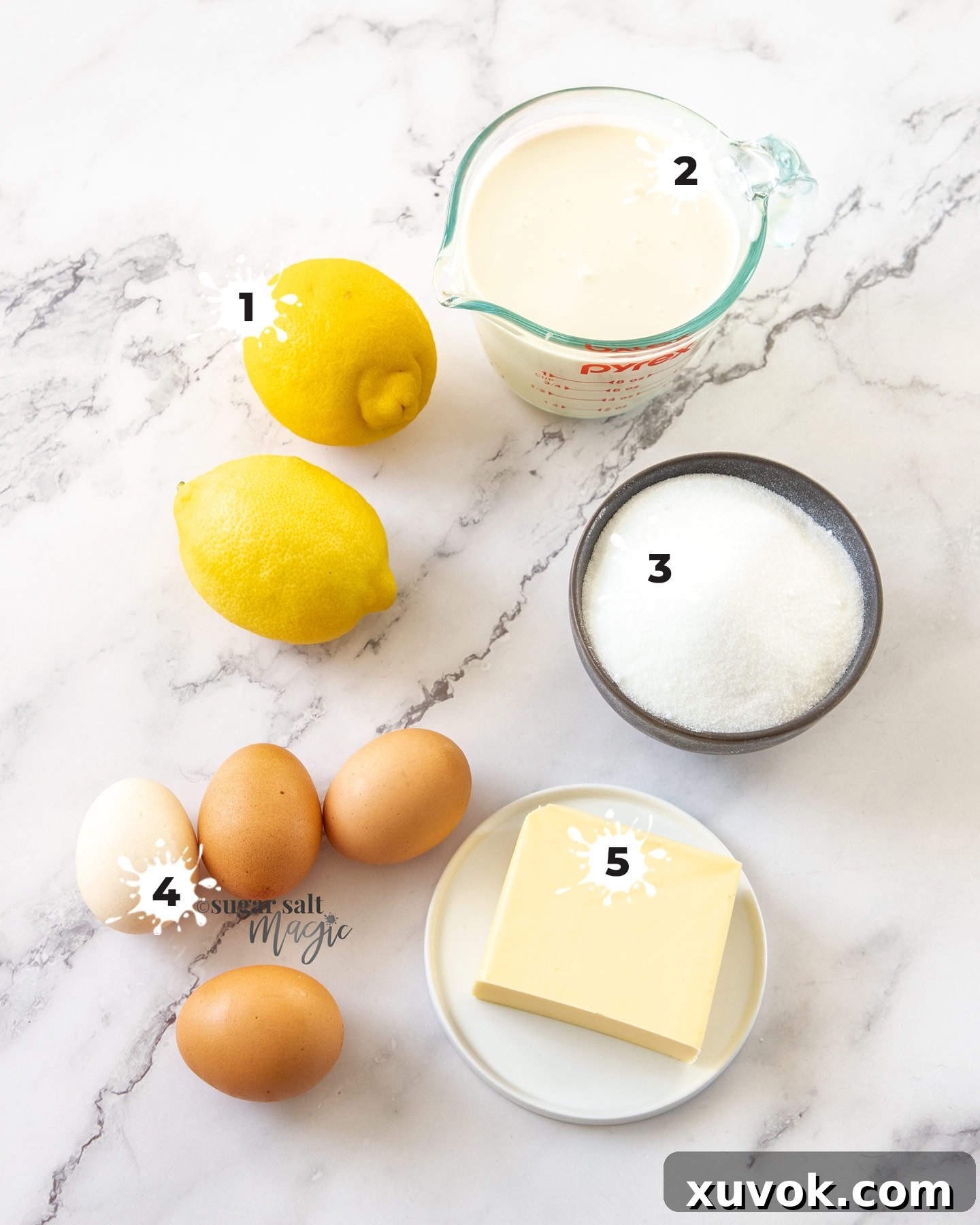 A collection of fresh ingredients for lemon mousse, including lemons, heavy cream, sugar, eggs, and butter, neatly arranged on a pristine marble background.