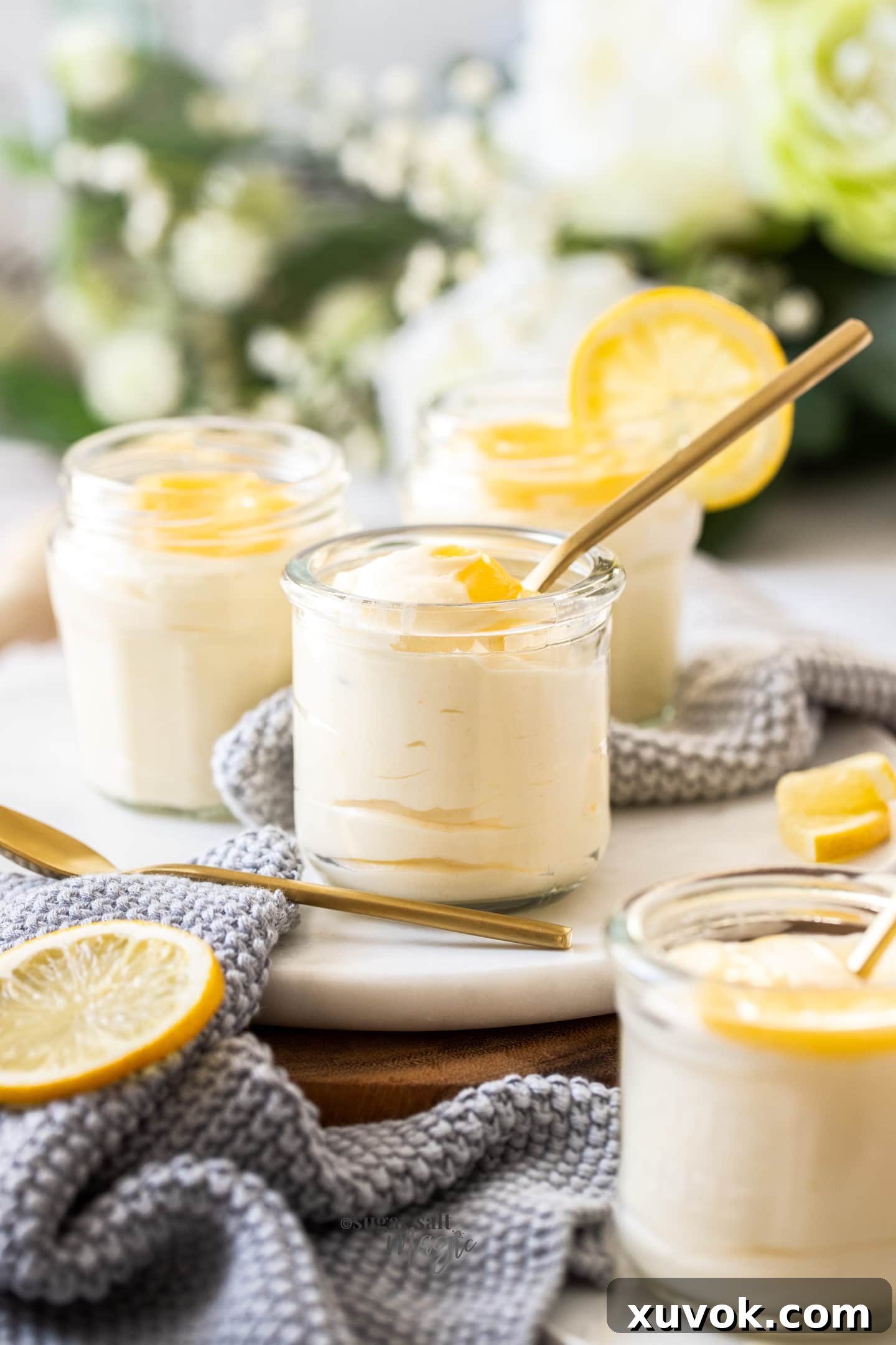 Four glasses of smooth lemon mousse elegantly presented on a white platter, ready for serving as a refreshing dessert.