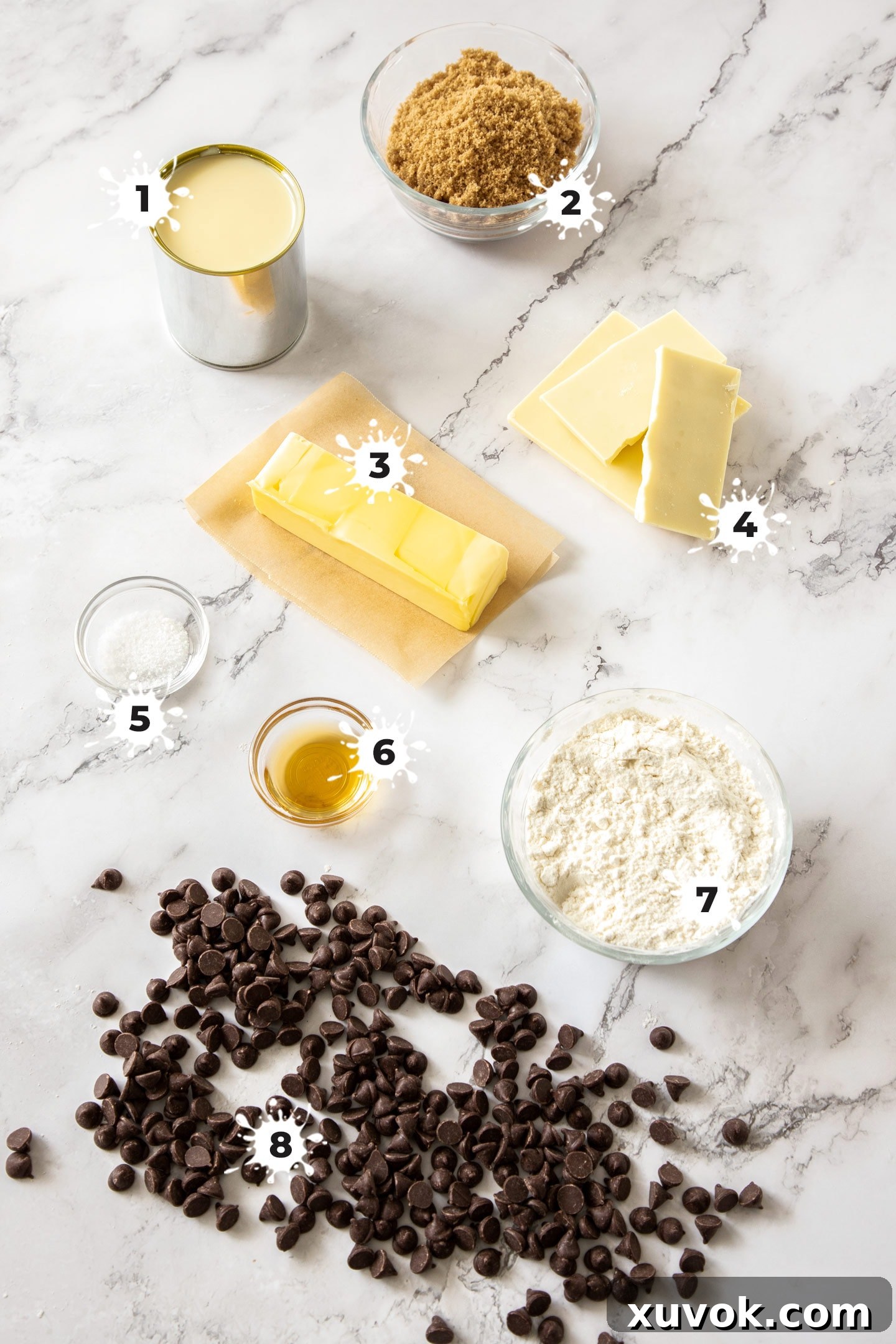 Key ingredients for Chocolate Chip Cookie Dough Fudge laid out on a clean marble surface, including flour, chocolate chips, brown sugar, and sweetened condensed milk, ready for preparation.