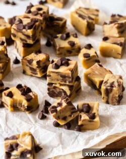 Close-up of neatly cut squares of homemade Chocolate Chip Cookie Dough Fudge on baking paper, highlighting its creamy texture and embedded chocolate chips.