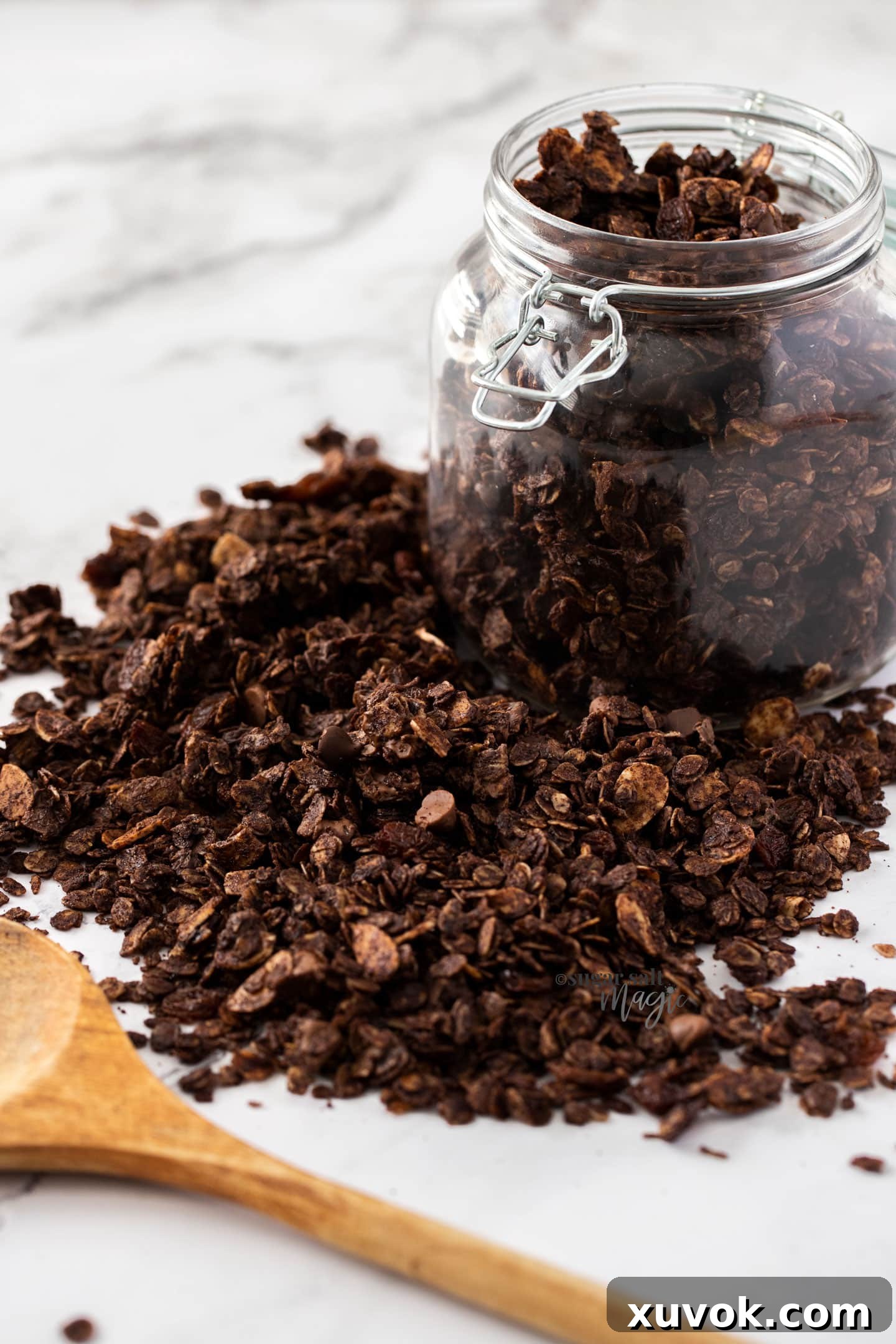 A glass jar filled with homemade chocolate granola, showcasing its rich color and chunky texture.