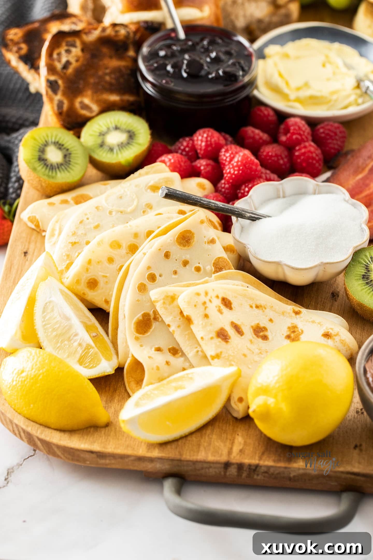 English pancakes with lemon and sugar on a breakfast platter, surrounded by other breakfast items.