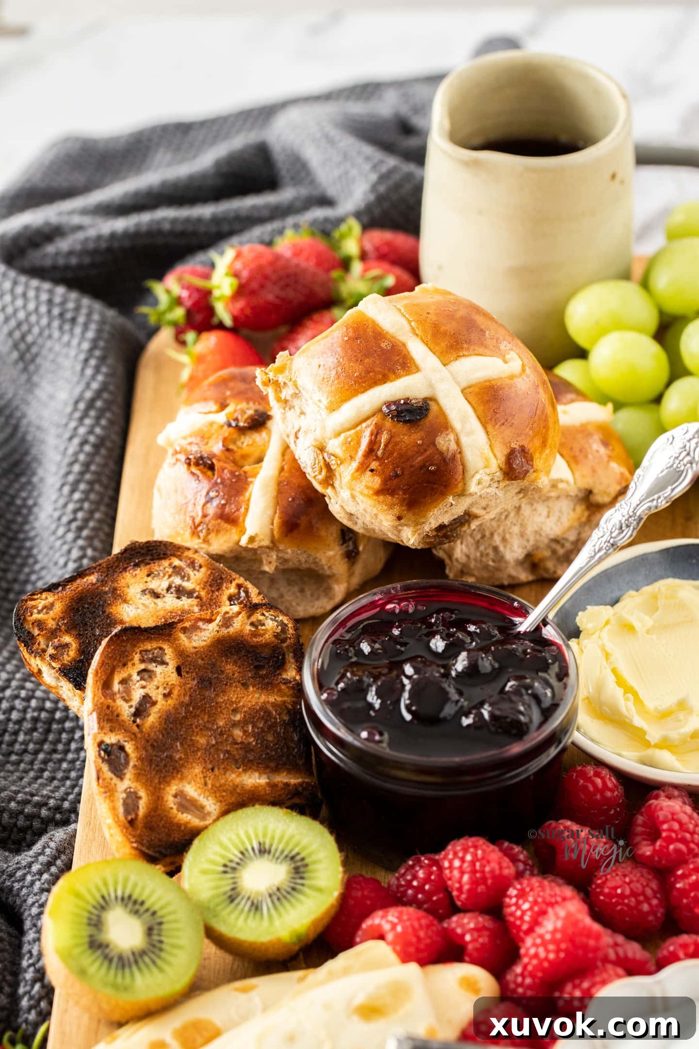 Hot cross buns, butter, and berries on a breakfast charcuterie board.