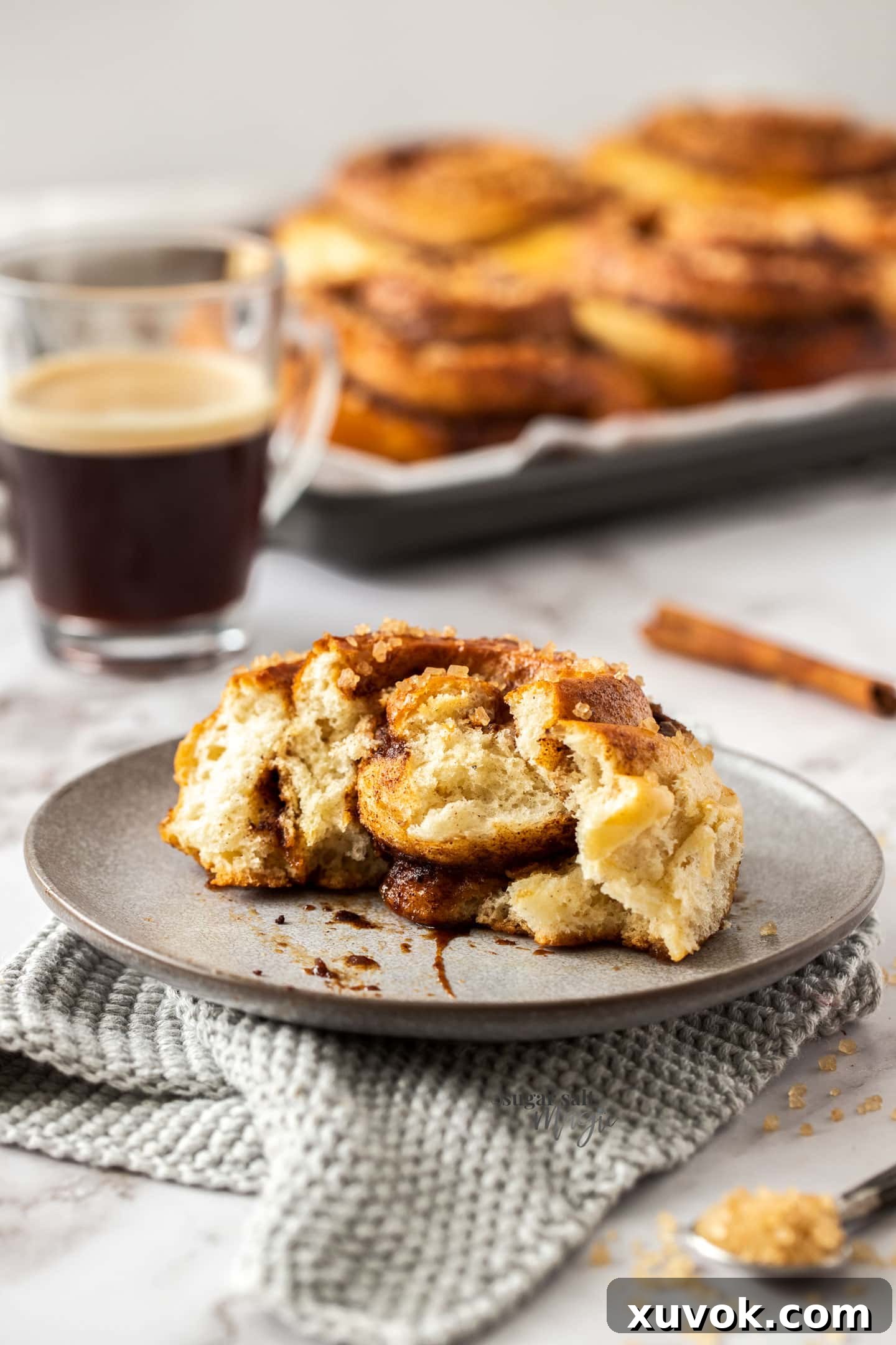 A jumbo Swedish cinnamon bun on a grey plate, freshly torn open to reveal its fluffy interior and luscious cinnamon filling.